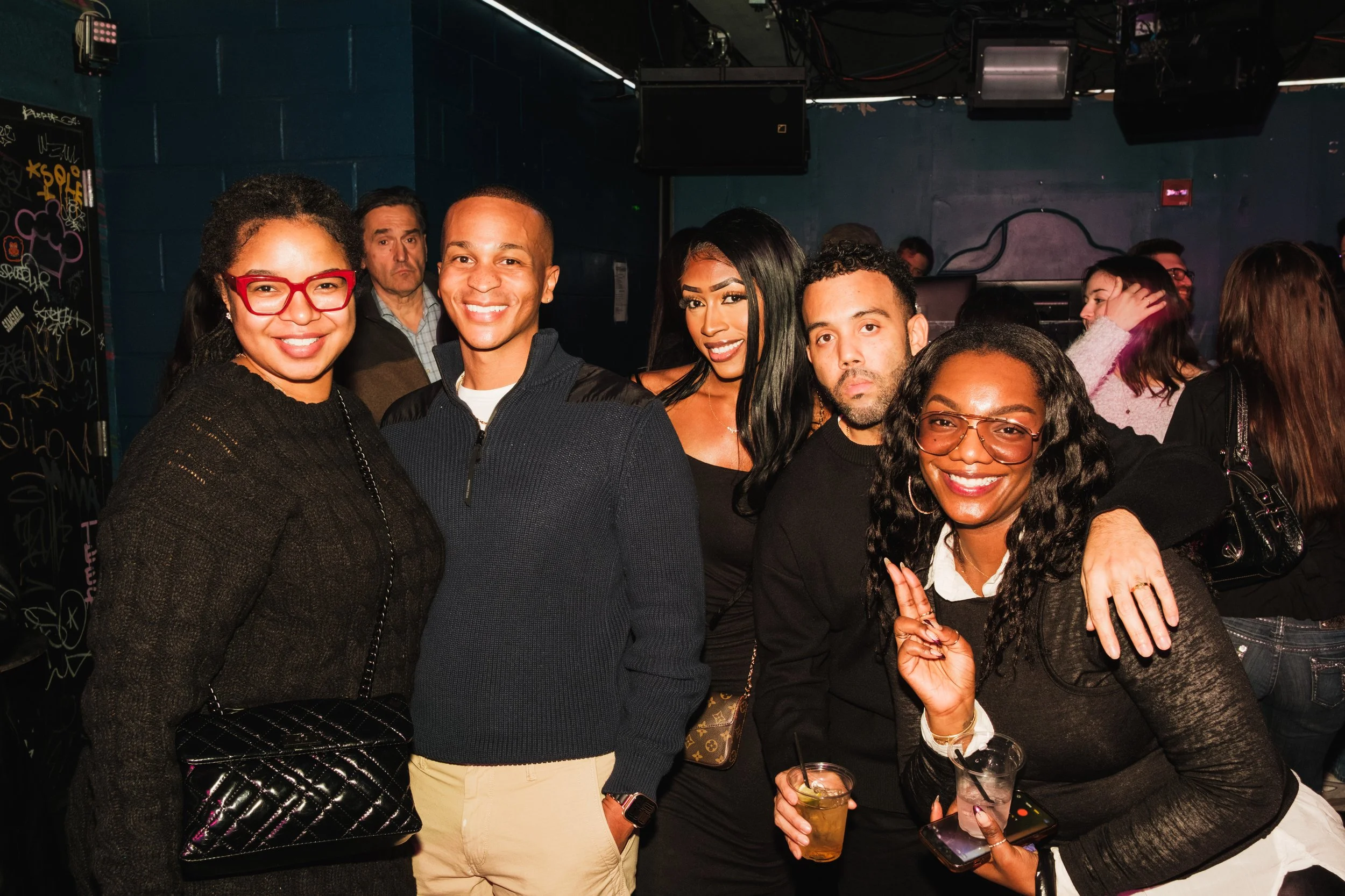 Group of five friends smiling and posing together at a party.