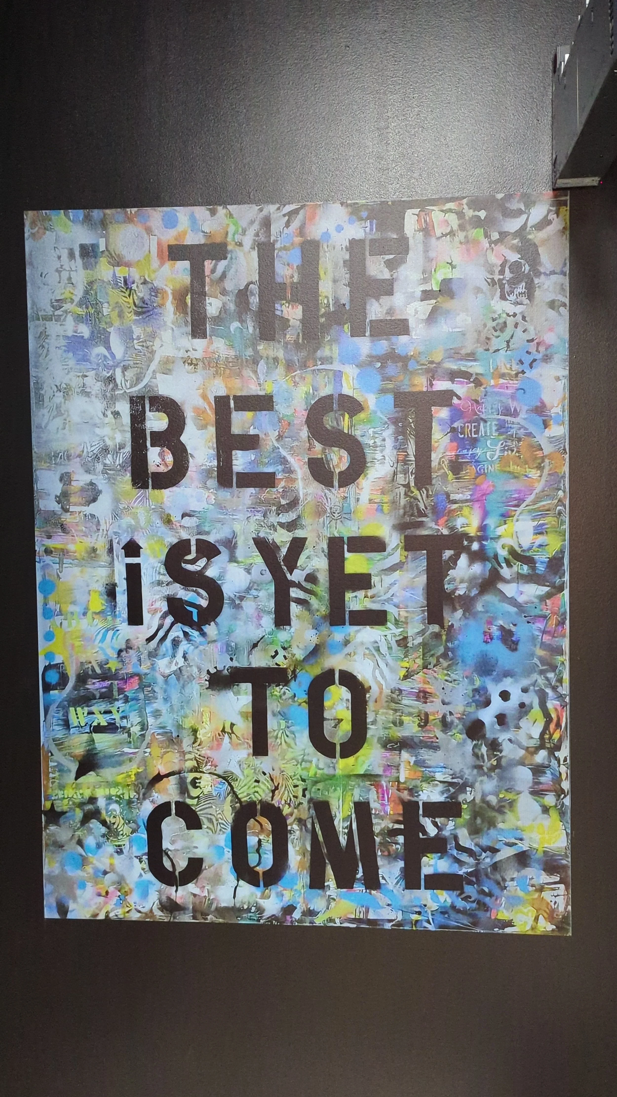 Colorful abstract wall art with bold black text that reads, 'THE BEST IS YET TO COME'.