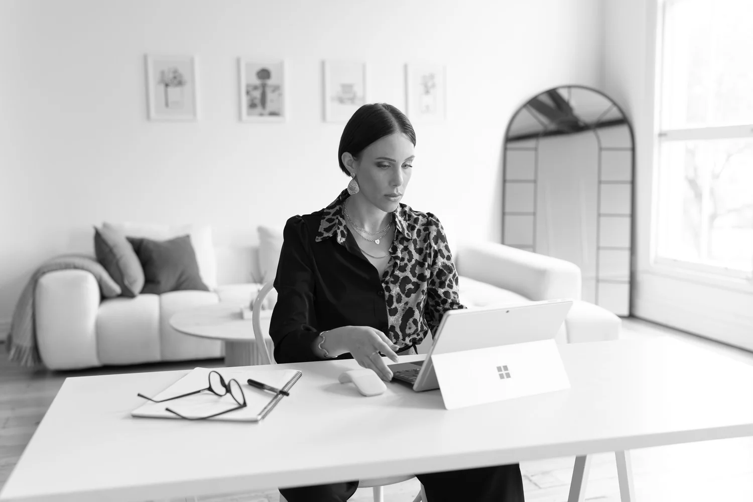 Black and white lifestyle portrait of a woman at her laptop