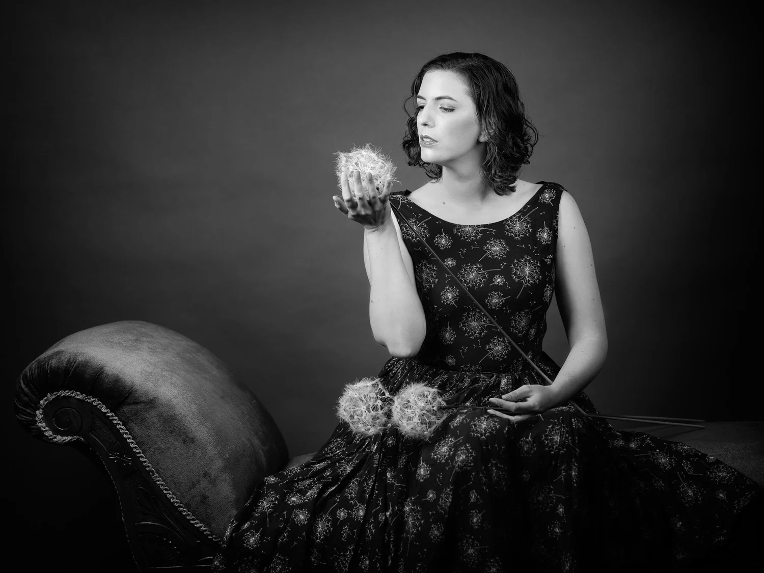 Black and white photo of a woman holding flowers beside a chaise longue