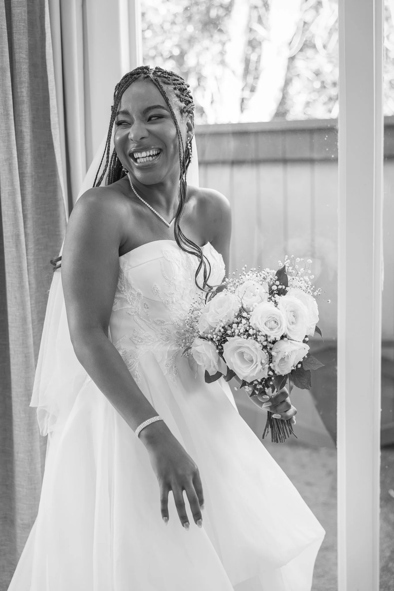 Black and white photo of Chiedza laughing in her gown