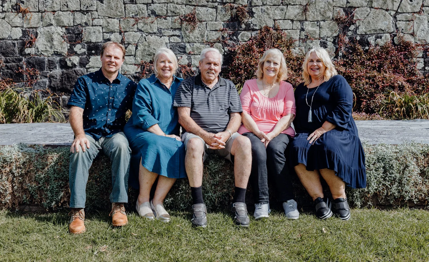Five family members sit together on a stone wall
