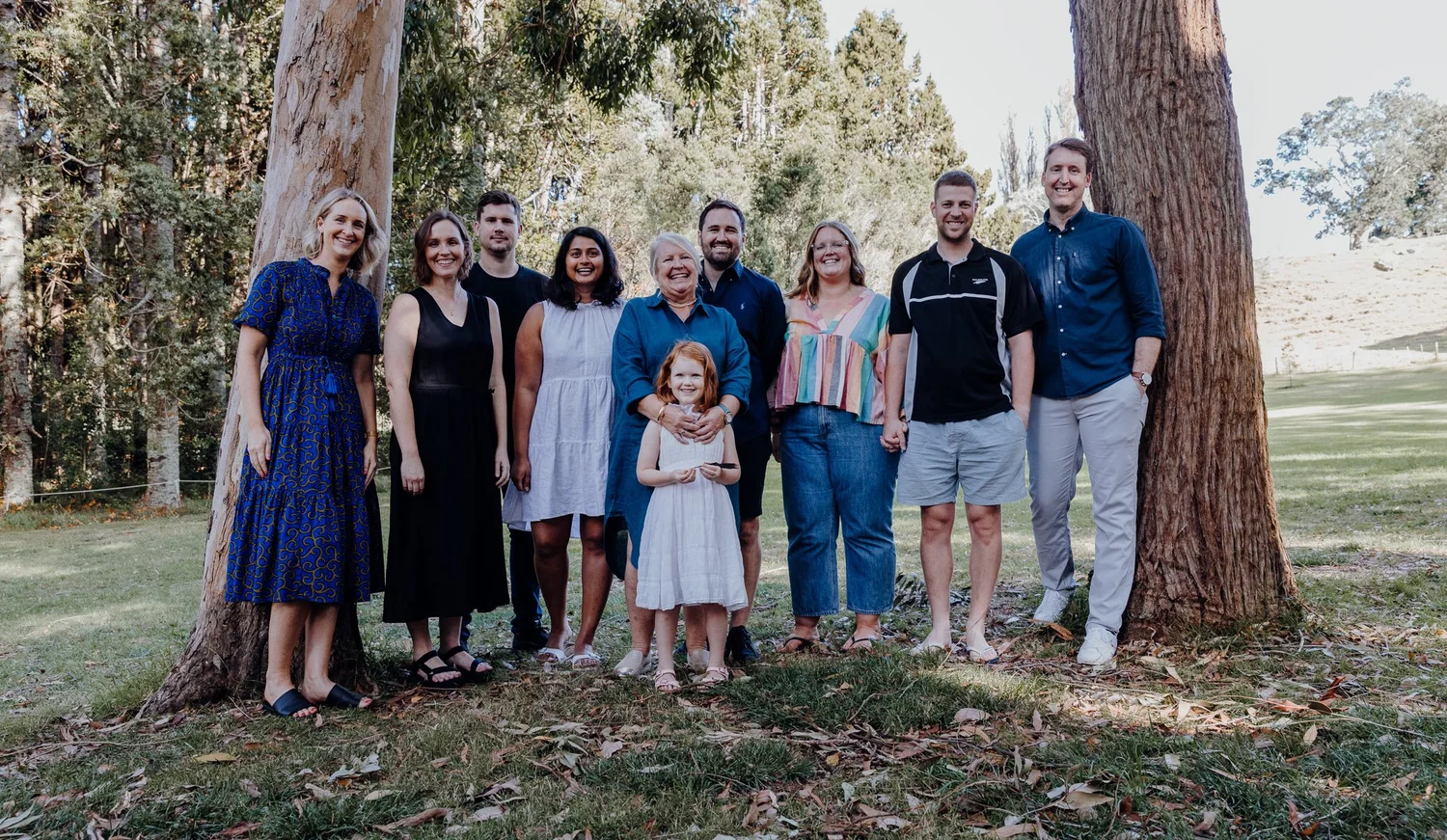 A family group with a young child between two trees