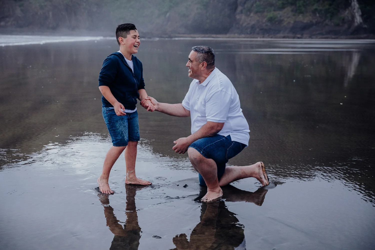 A boy and a man playing on the wet sand