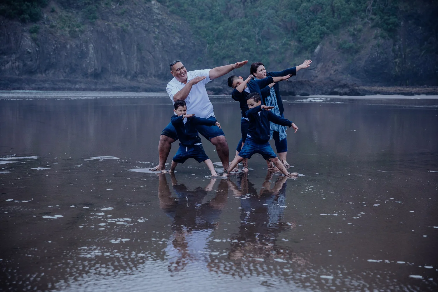 The family play-fights on the wet sand