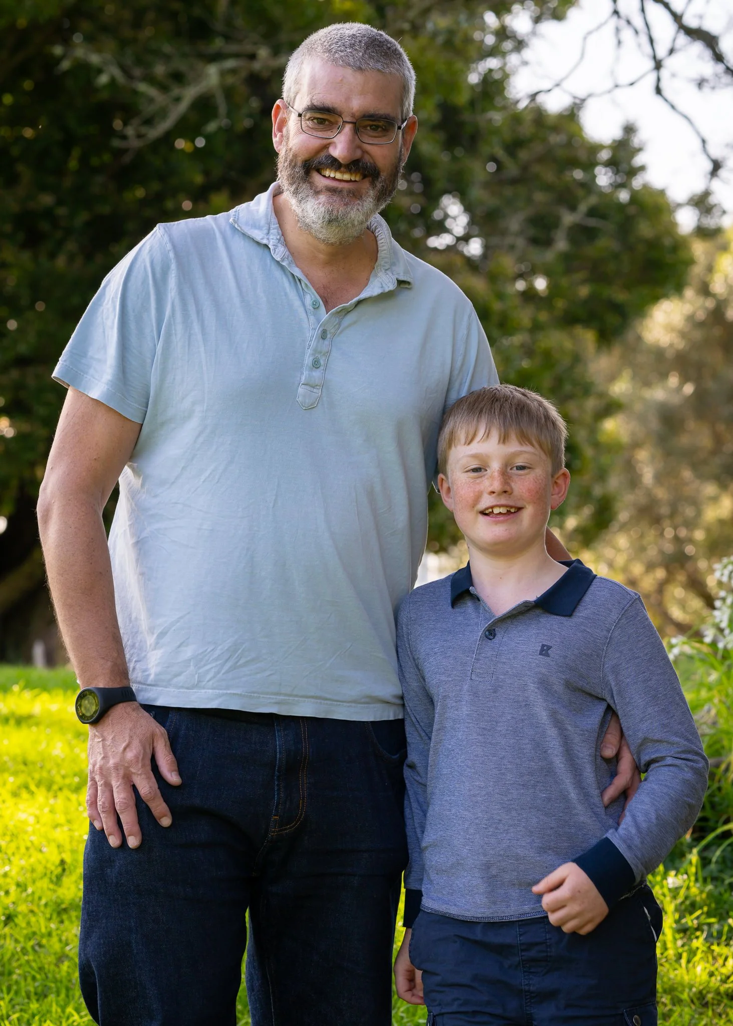 A father and son smile together in the park