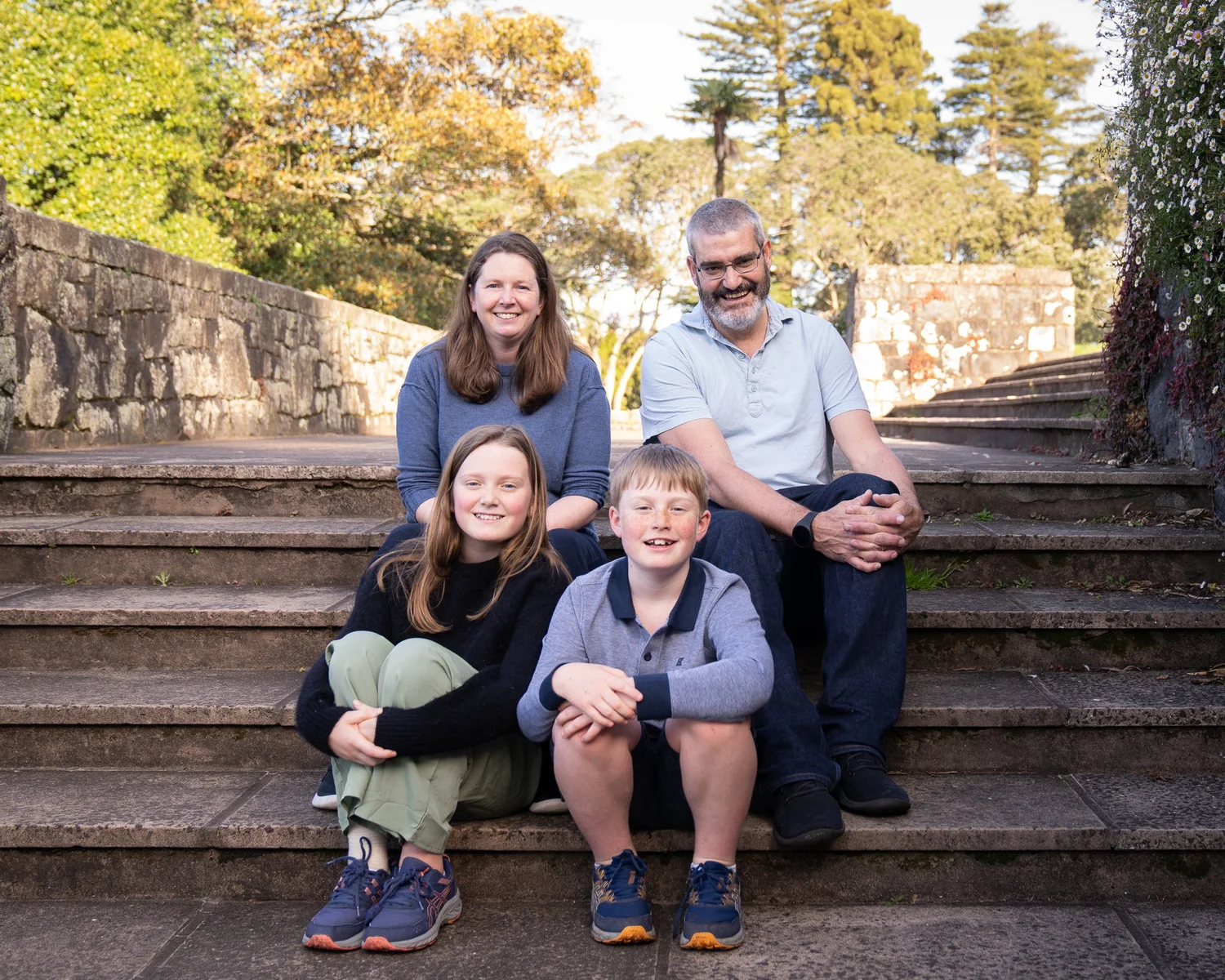 The family sits together on stone steps at Cornwall Park