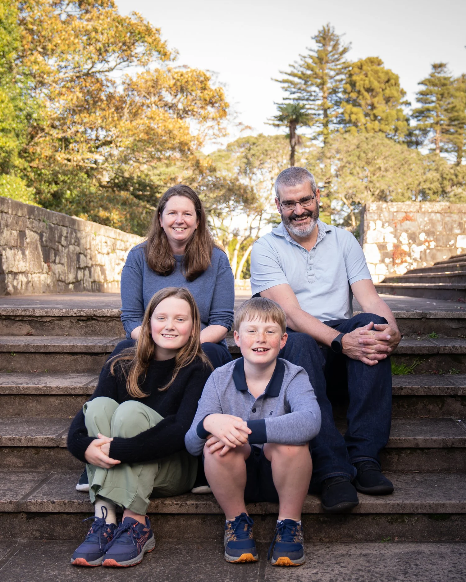 The family smiles together on the stone steps