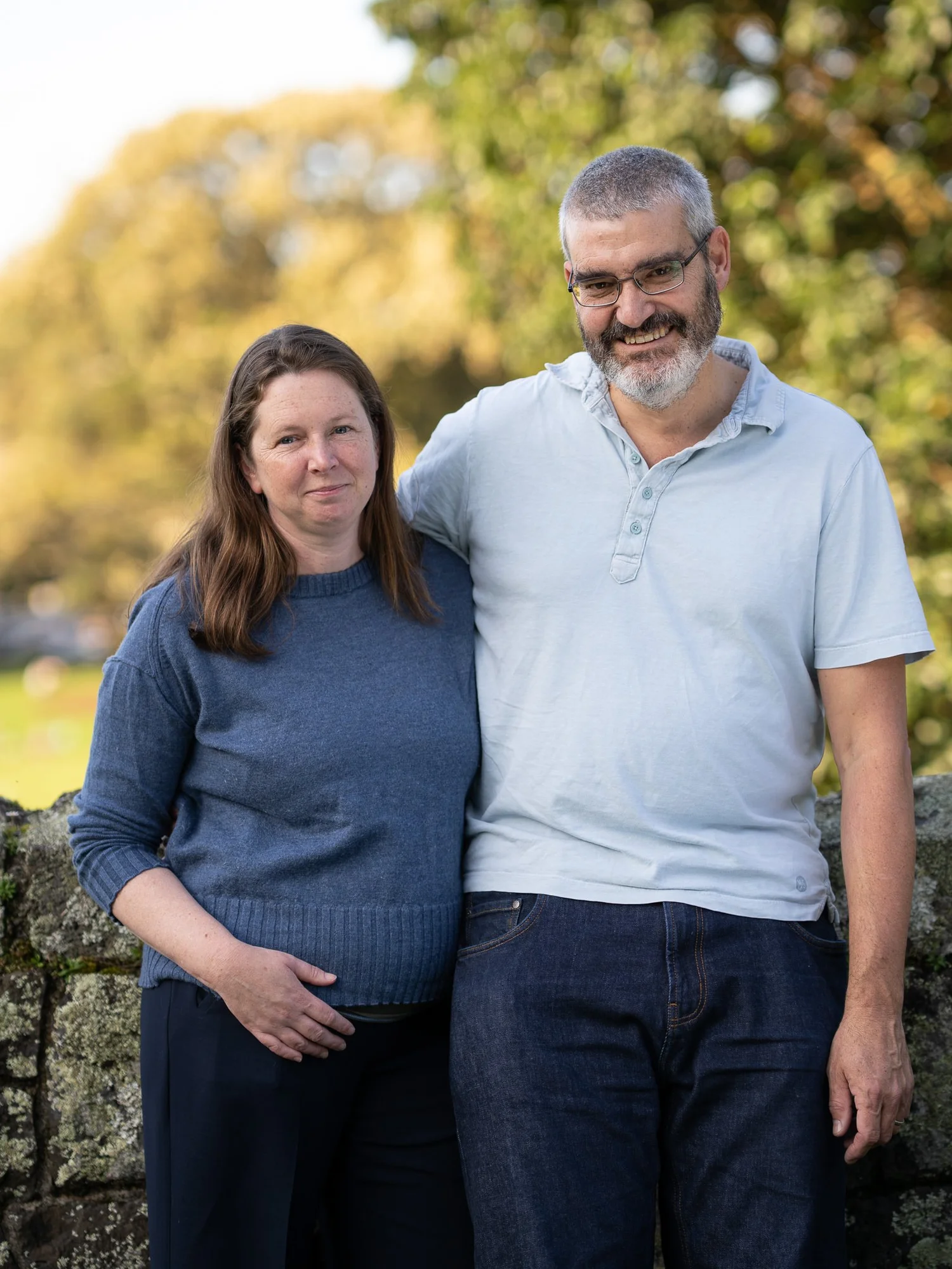 The parents smile at the camera in warm evening light