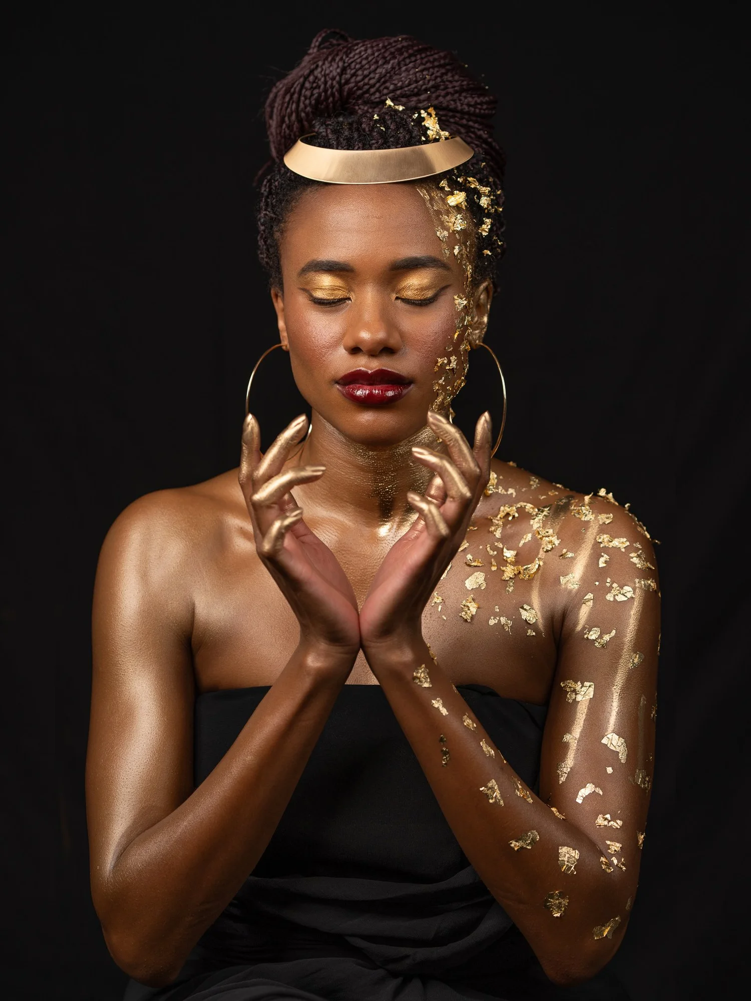 Ty with eyes closed and hands crossed, covered in gold leaf