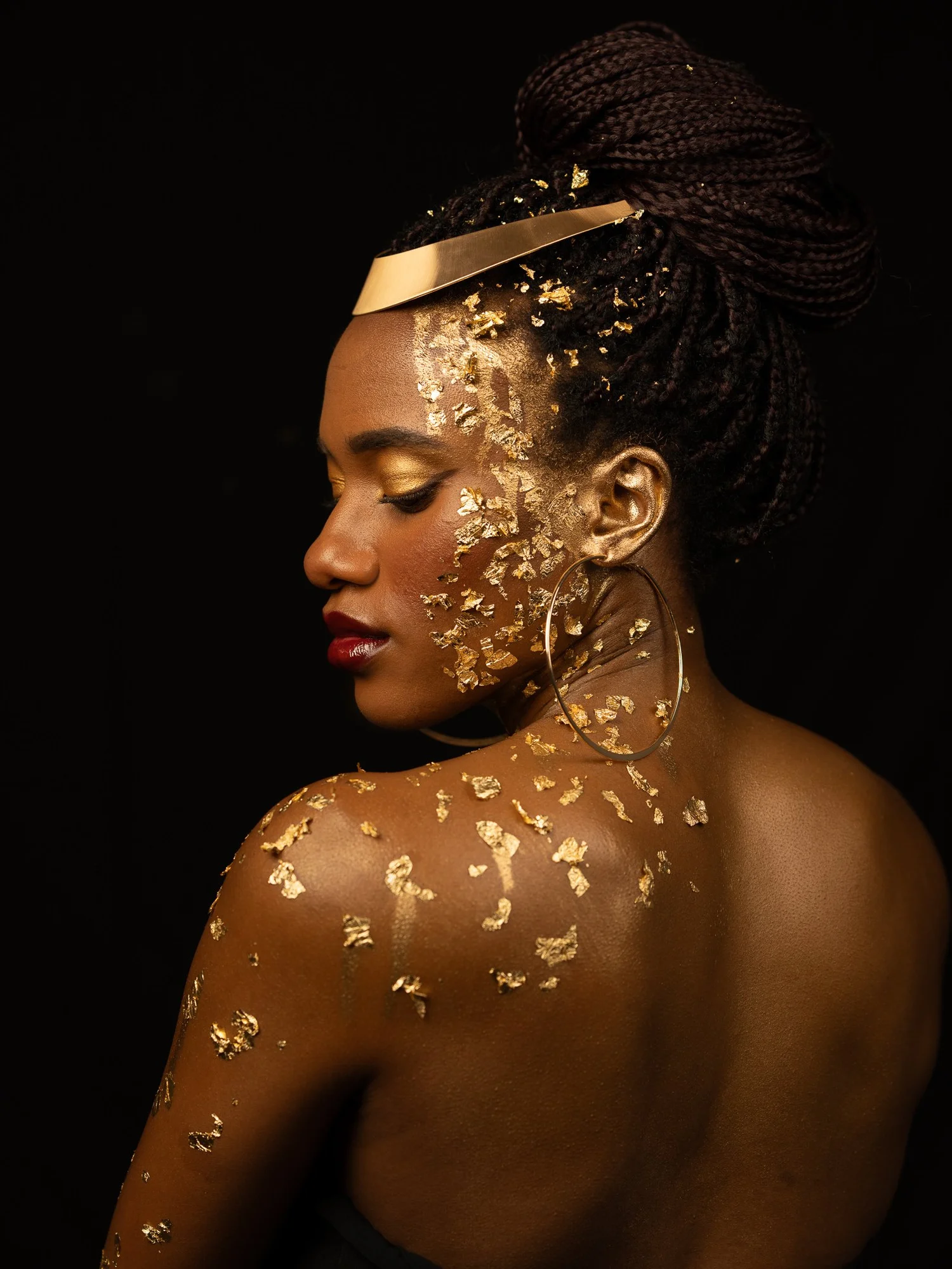 Ty looks over a gold-leafed shoulder in a studio portrait