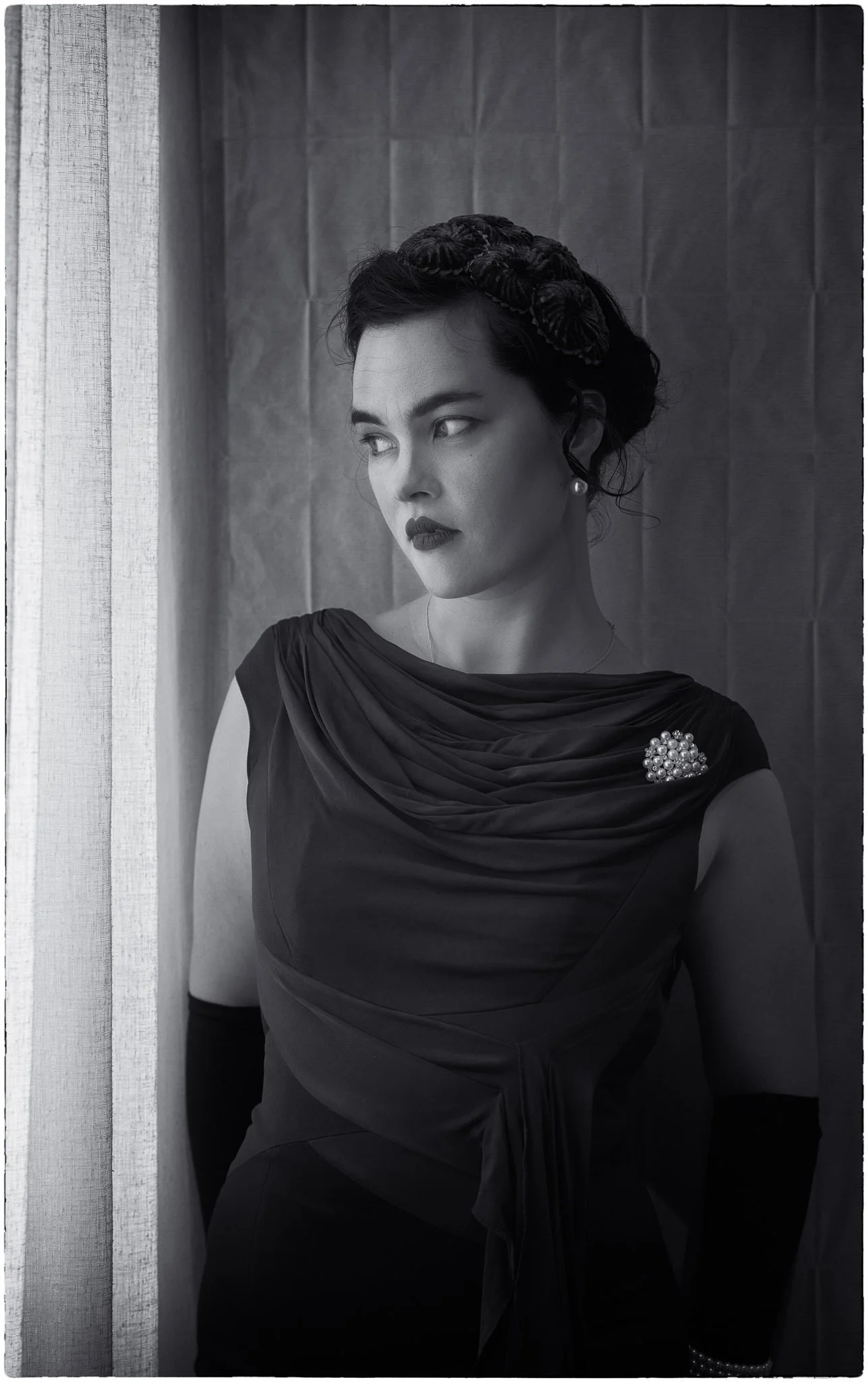 Black and white photo of Anita in long gloves by a window