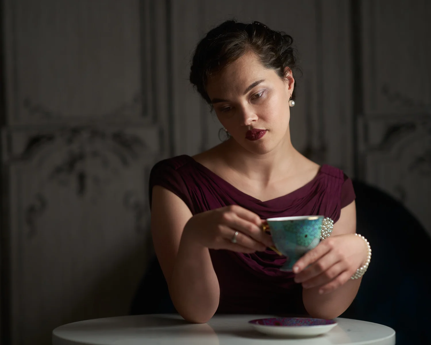 Anita holds a teacup at a small round table