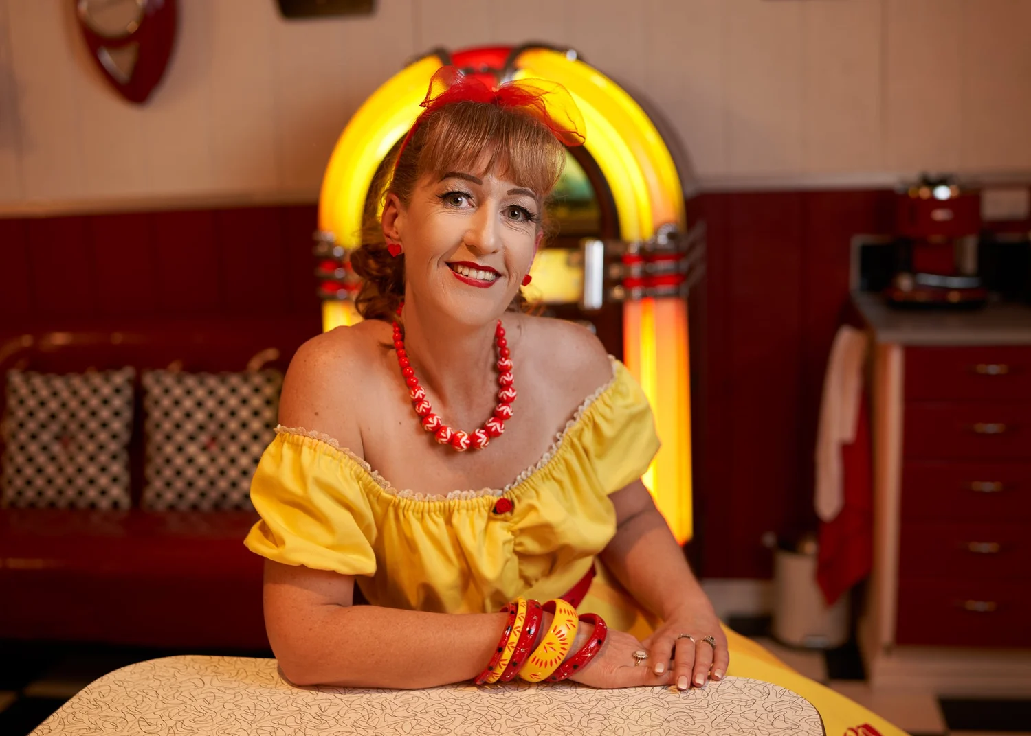 Sandy at a table in front of a glowing jukebox