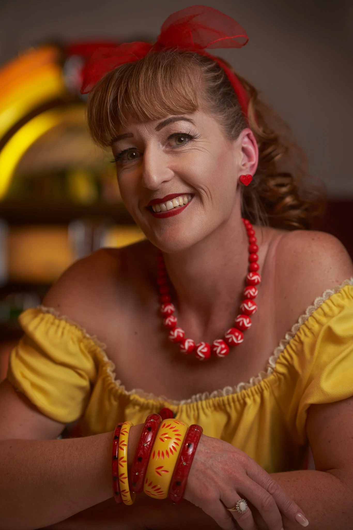 Close portrait of Sandy smiling in red beads and bangles