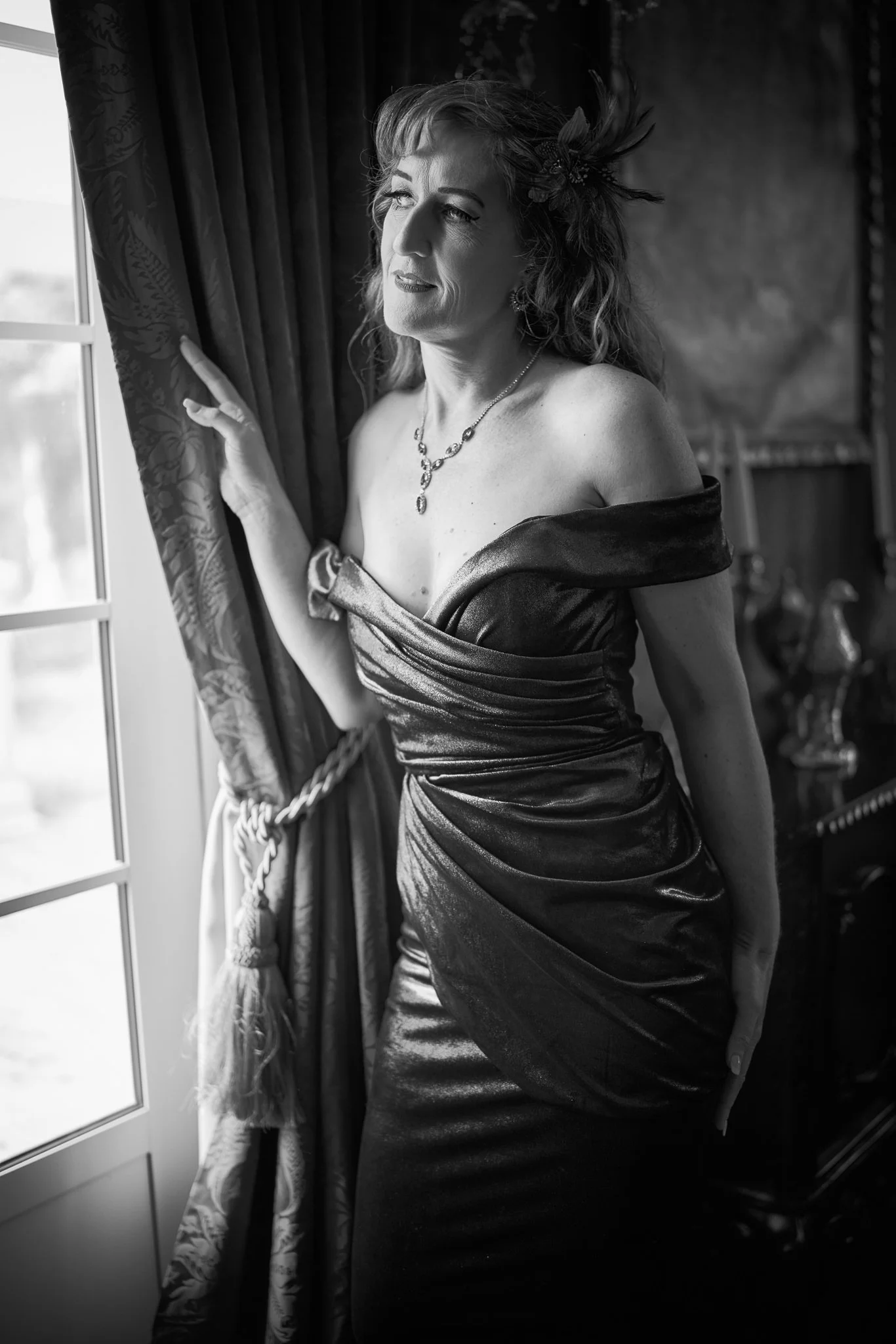 Black and white photo of Sandy by the window in a satin gown