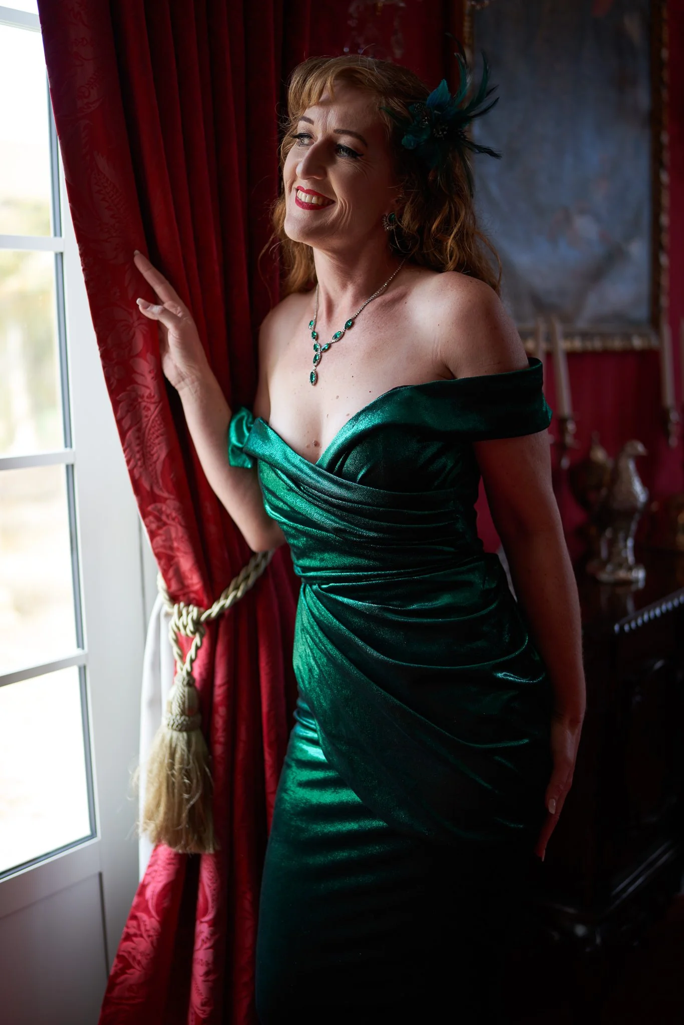 Sandy smiles in an emerald gown beside red curtains