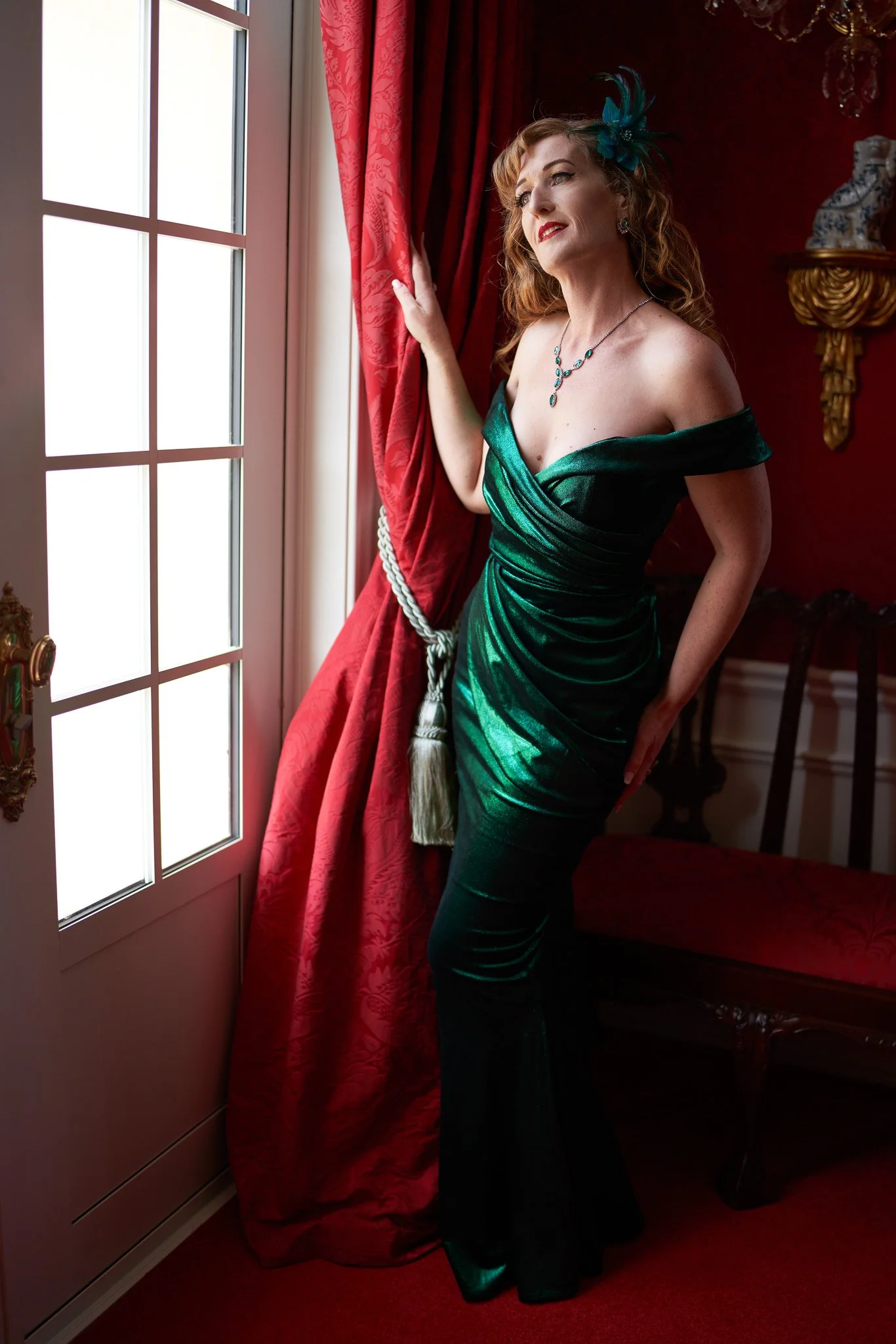 Full-length photo of Sandy in green satin by a tall window