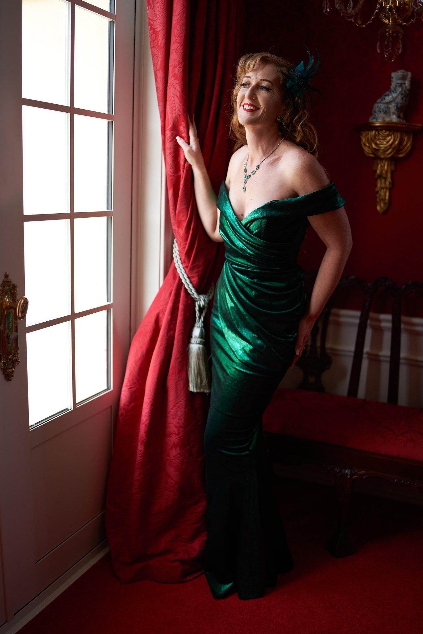 Sandy poses by the window in an emerald gown