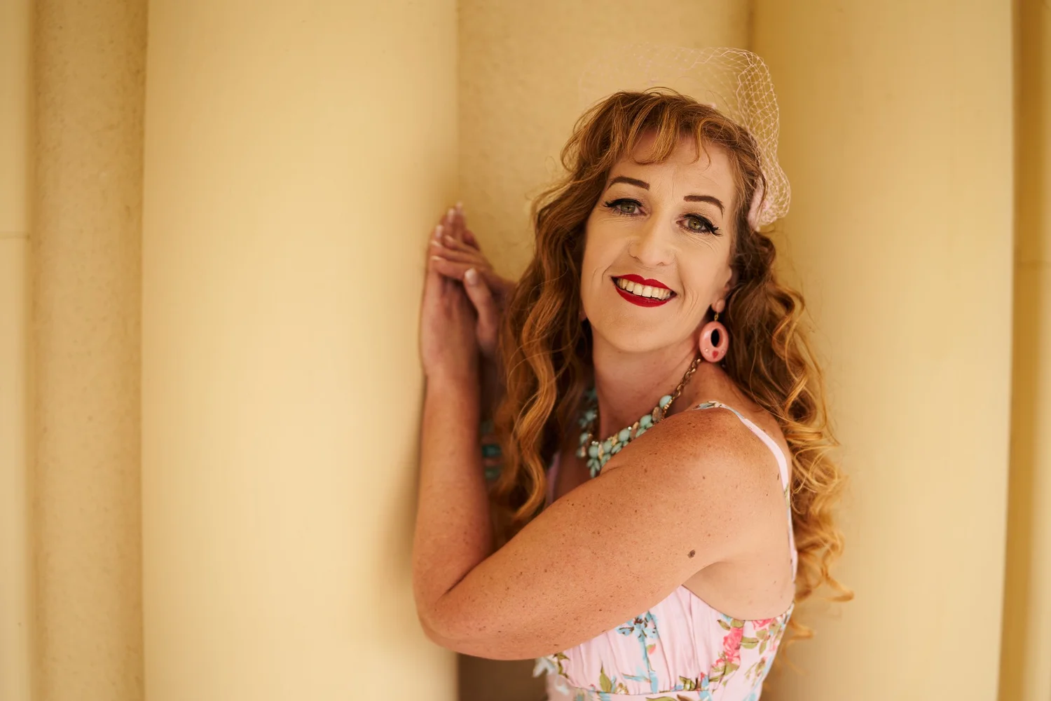 Sandy leans against a column in a floral dress