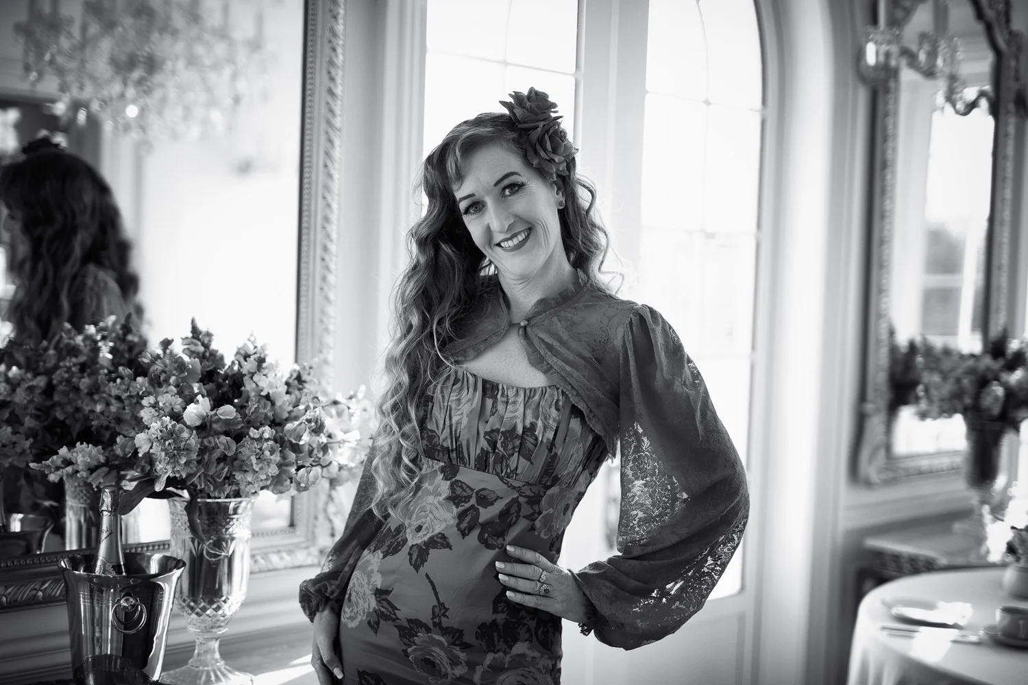 Black and white photo of Sandy beside a chandelier