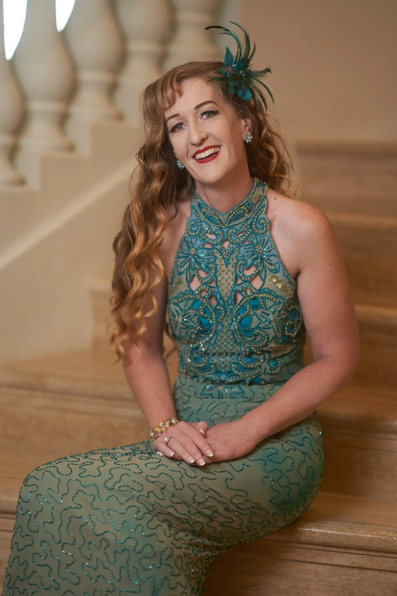 Sandy sits on the stairs in a beaded green gown