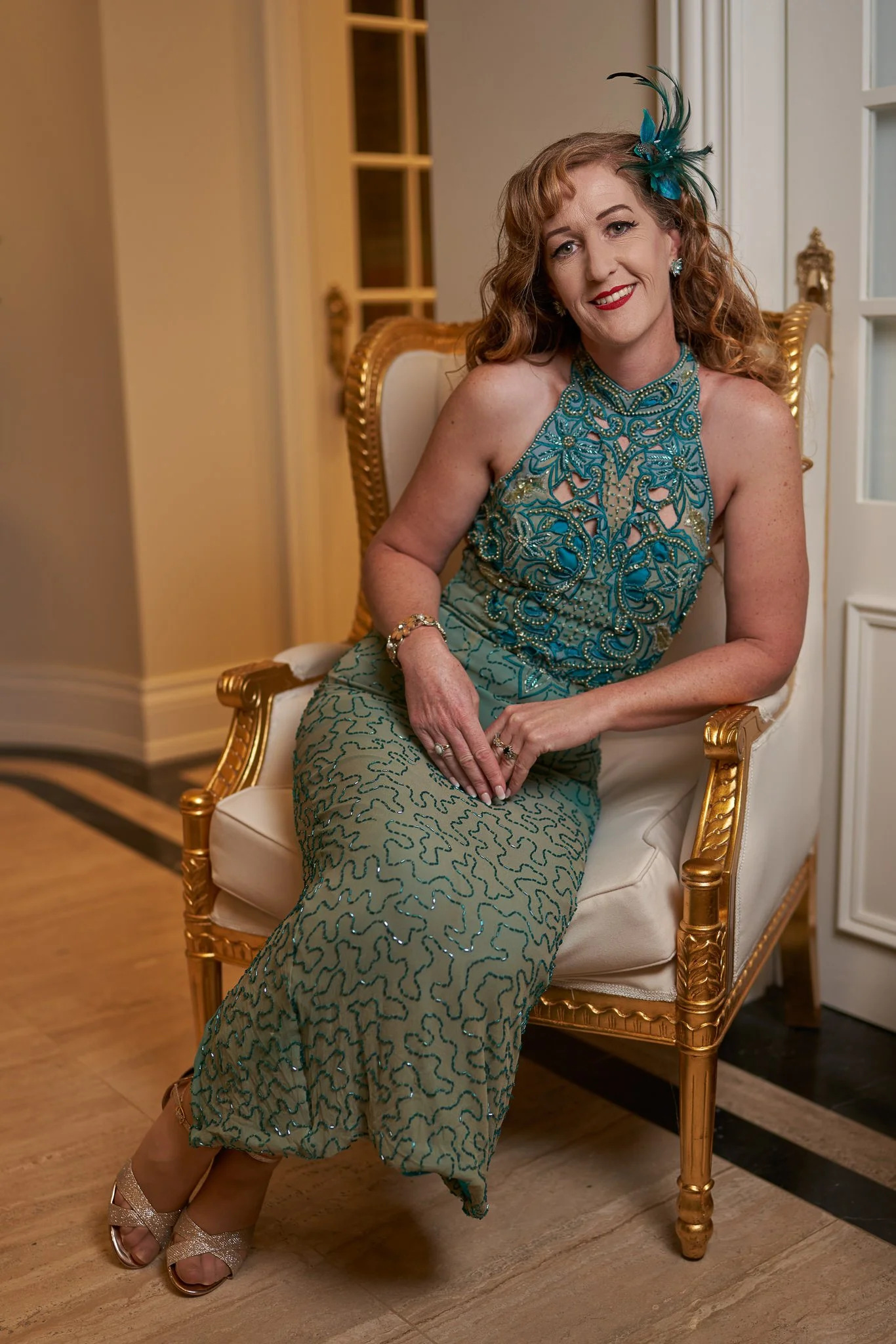 Sandy seated in a gilded chair in a green gown
