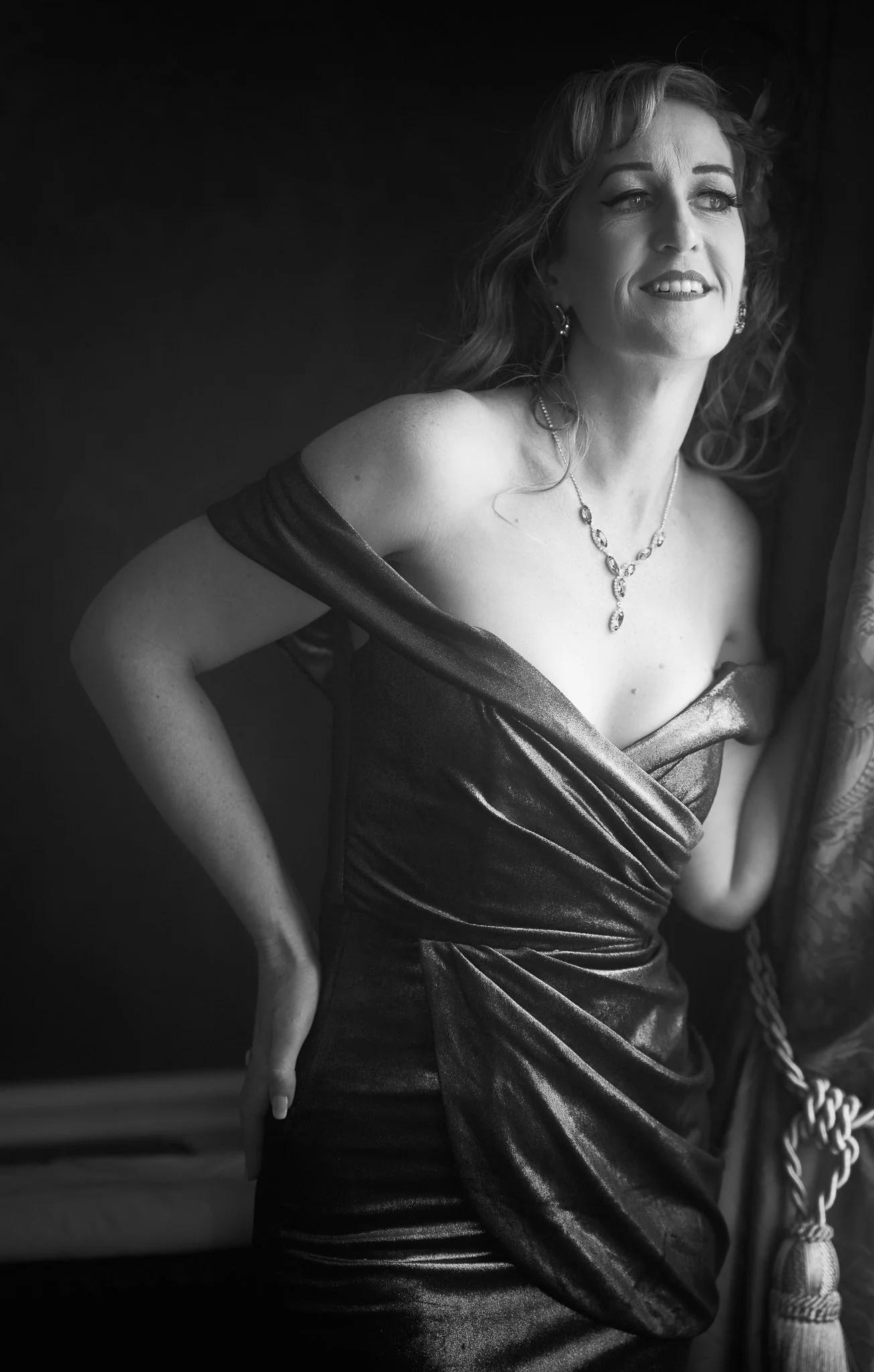 Black and white photo of Sandy beside a curtain
