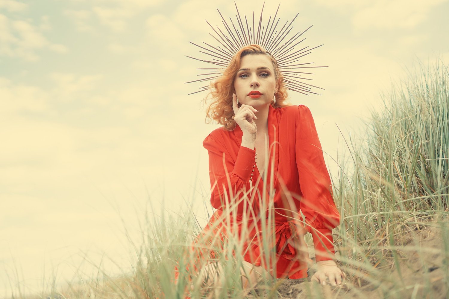 A model in red wearing a spiked golden crown in the dunes