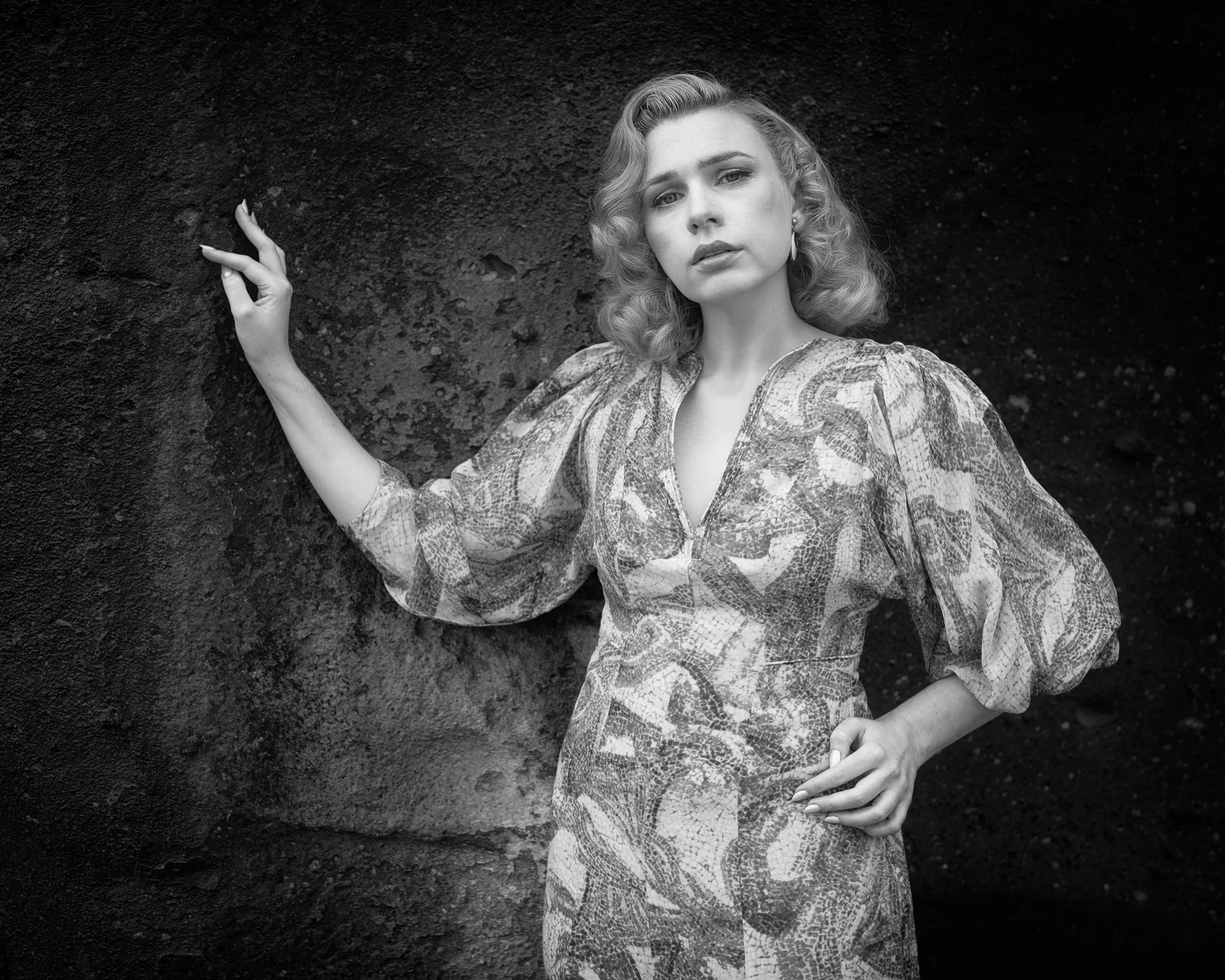 Black and white photo of a model against a rock wall