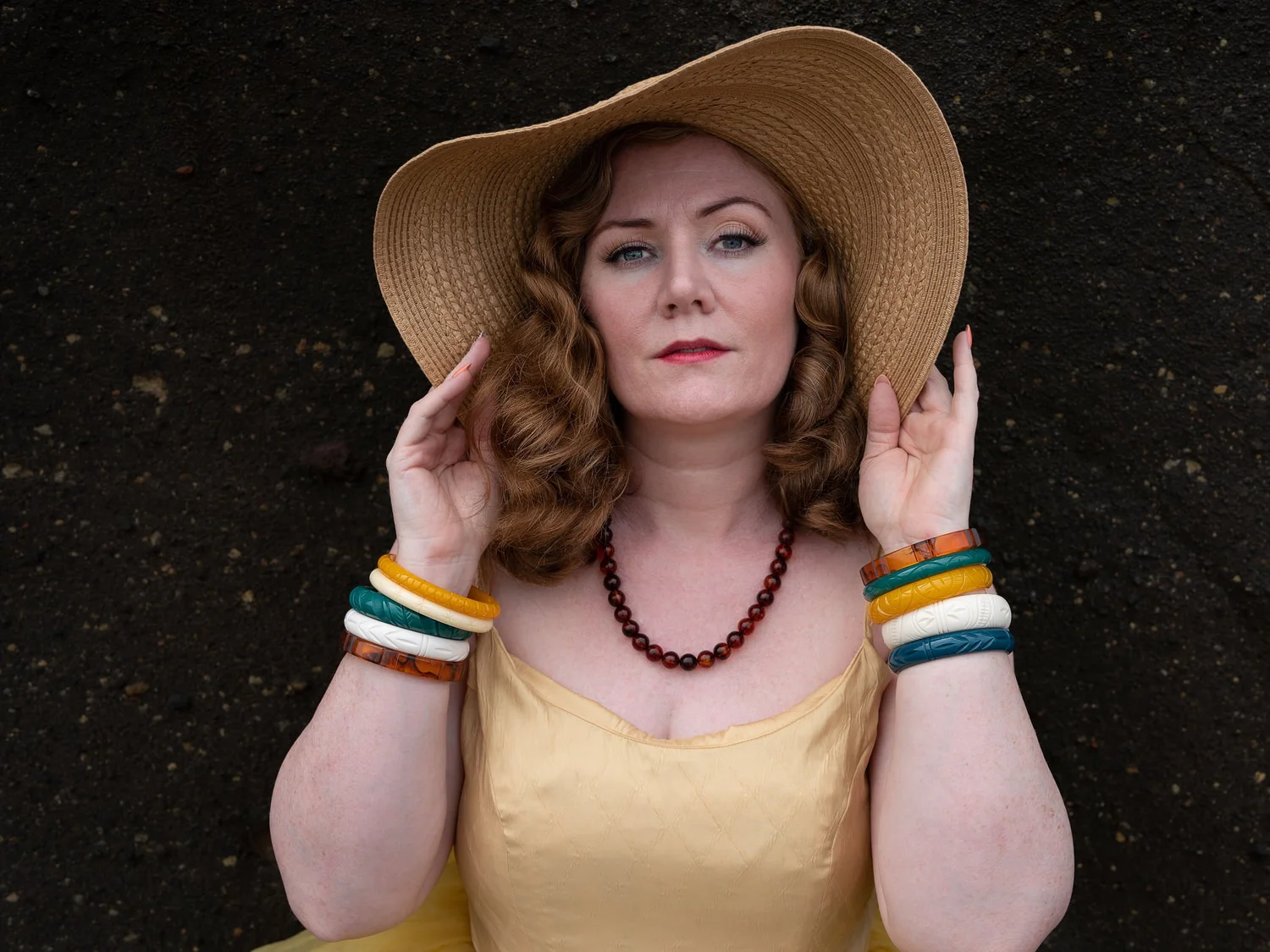 A model in a wide straw hat and colourful bangles