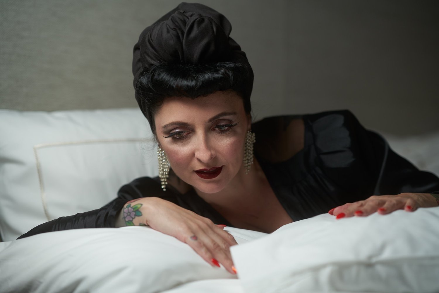 Viv leans on white pillows with red lips