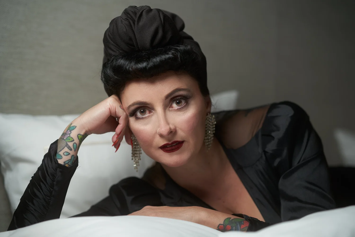 Viv rests on white pillows in black lace at the Fable