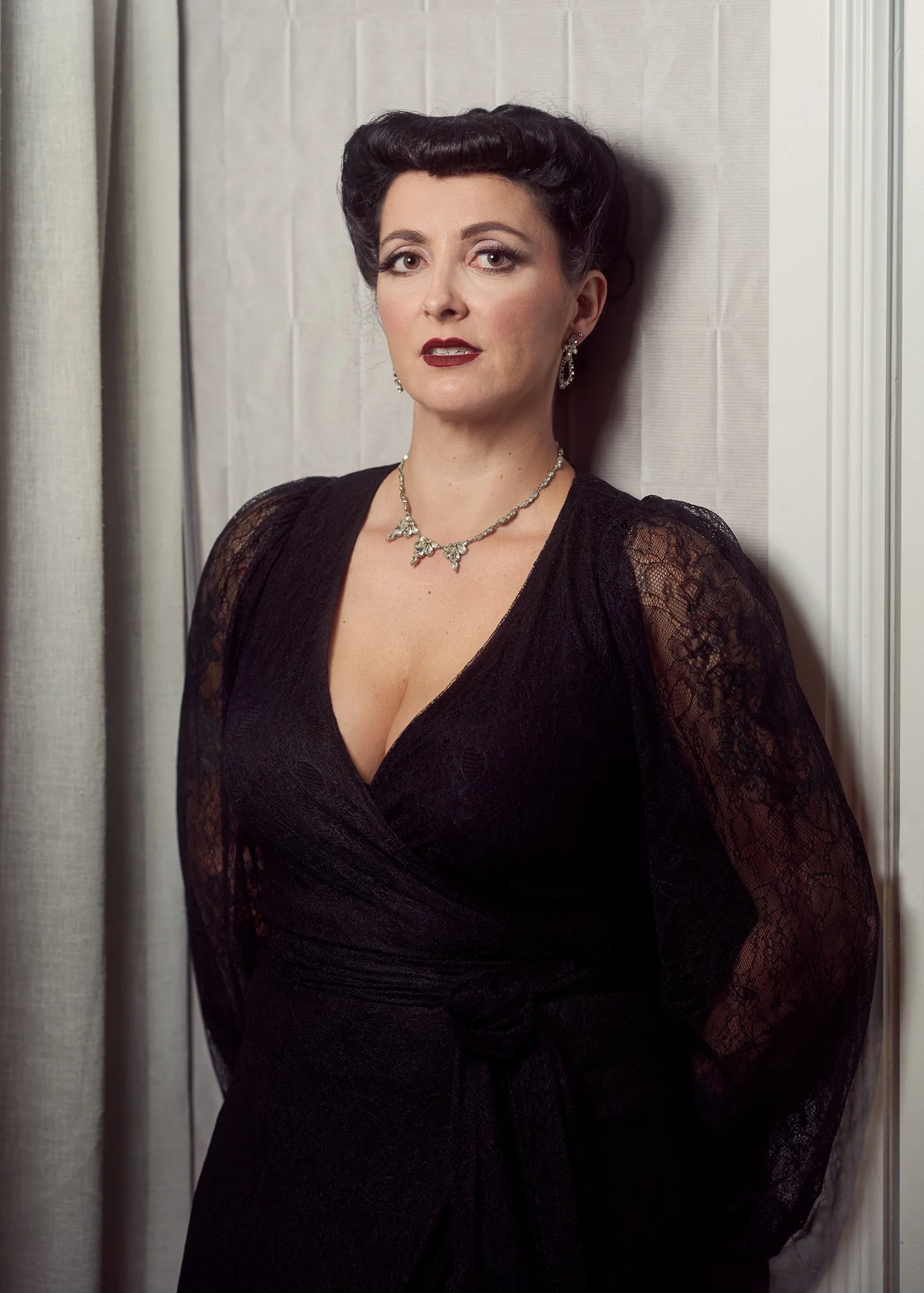 Viv in black lace by a pale curtain