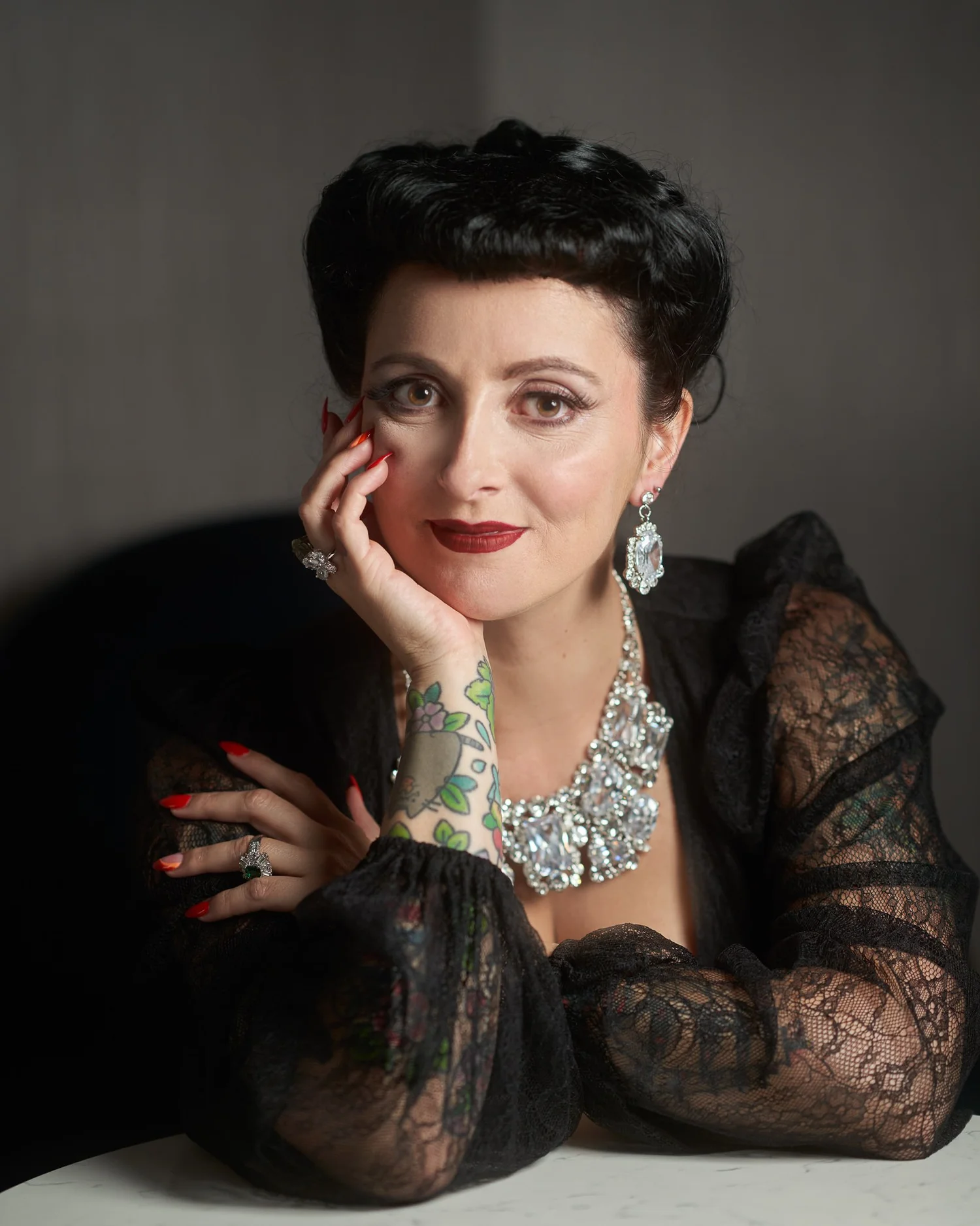 Viv smiles with her chin on her hand in sparkling jewellery