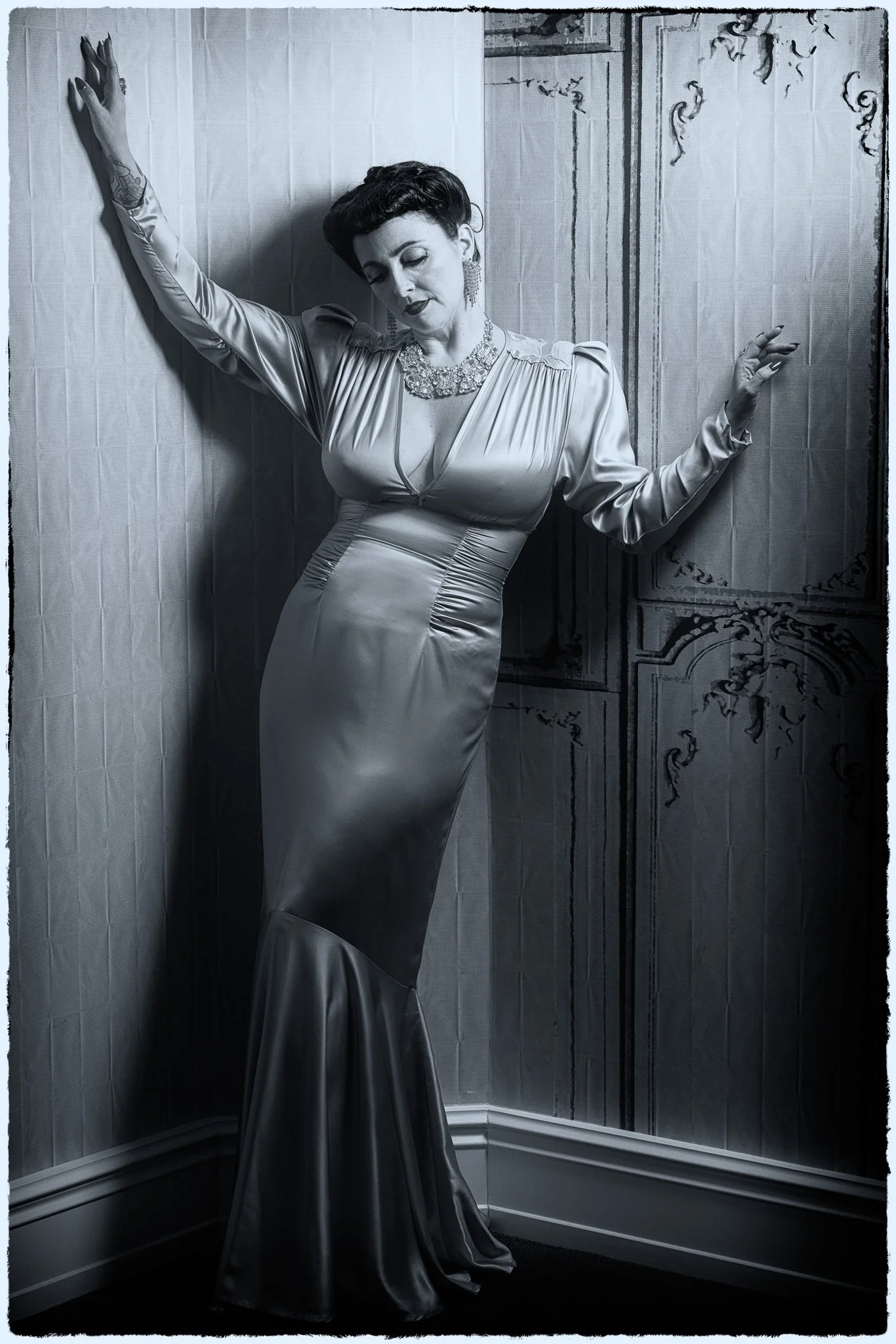 Black and white photo of Viv in a satin gown against a wall