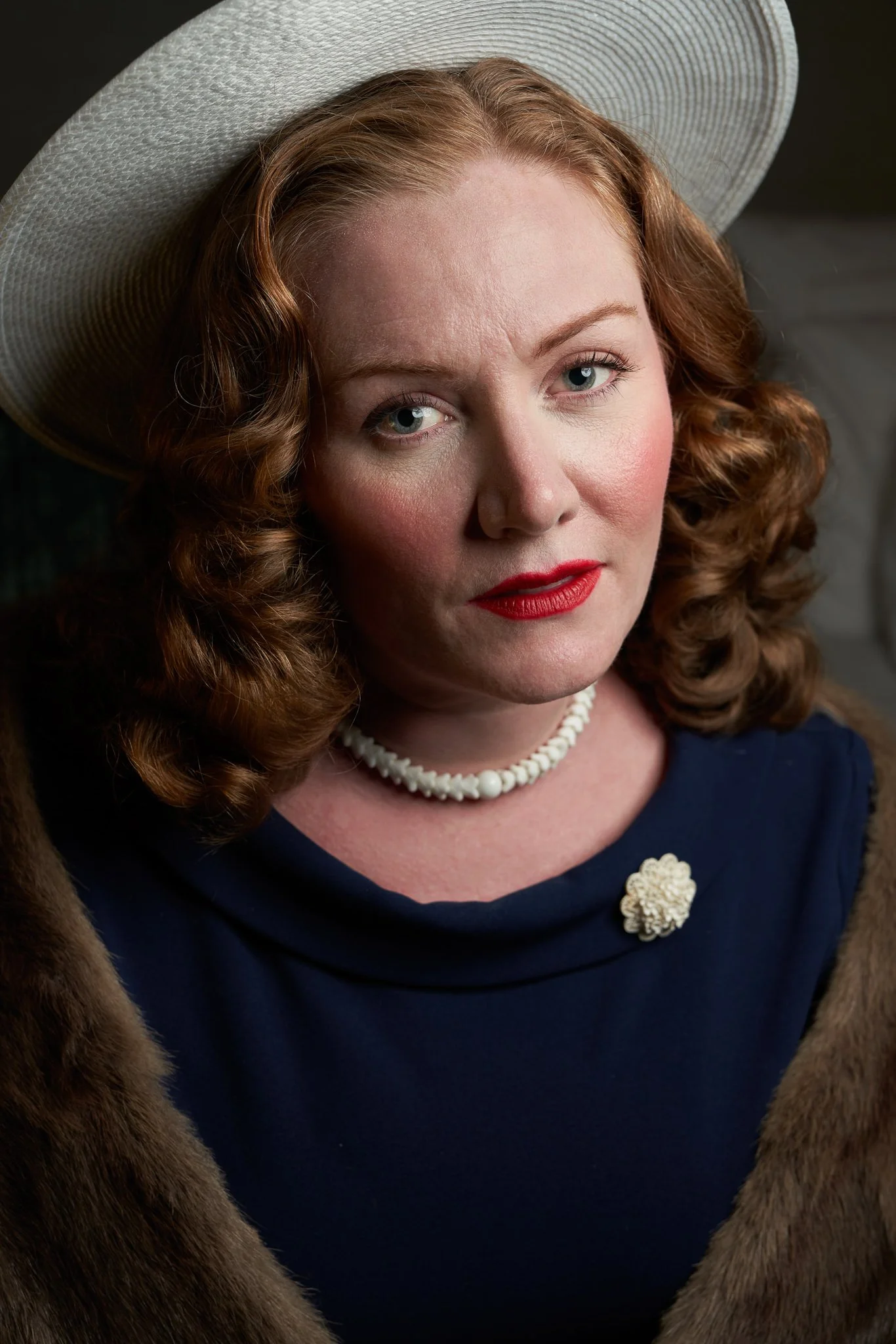 Close portrait of Laura in a white hat and pearls