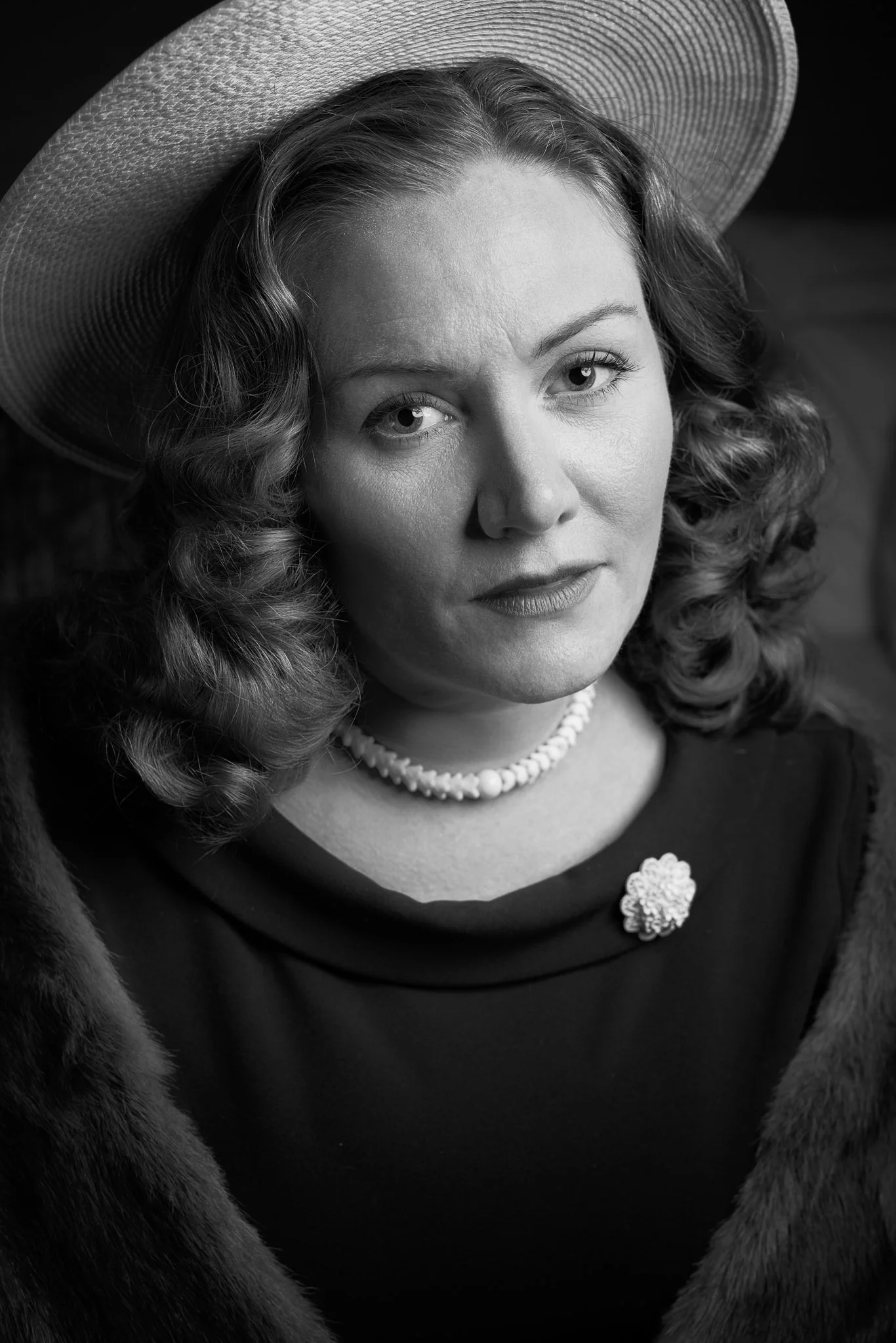 Black and white close portrait of Laura in a hat and pearls