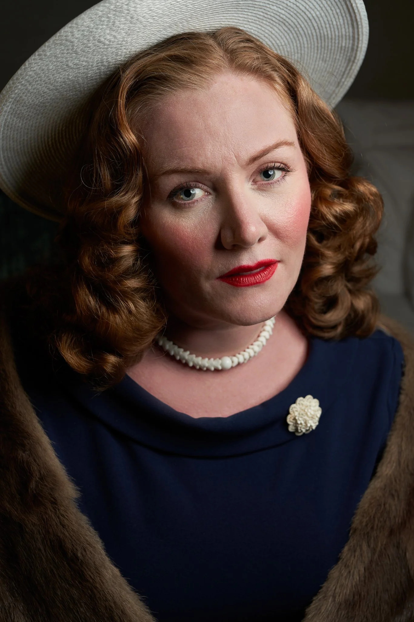 Laura in a white hat, pearls and navy dress