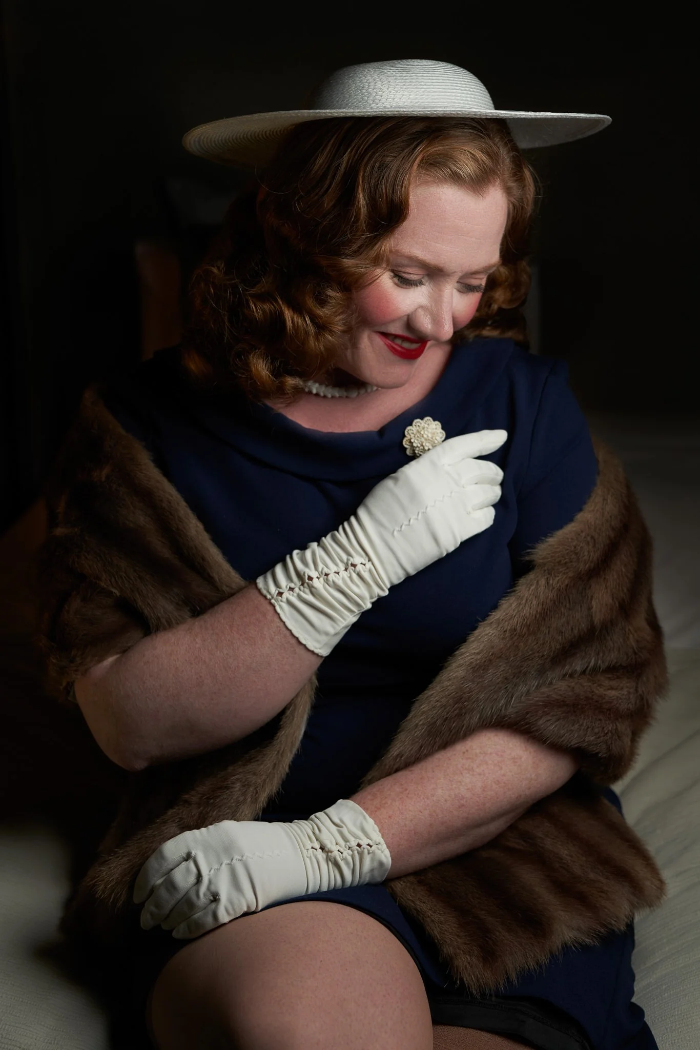Laura looks down while adjusting her white gloves