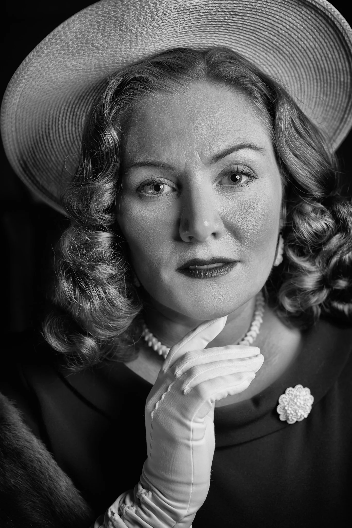 Black and white photo of Laura with a gloved hand at her chin
