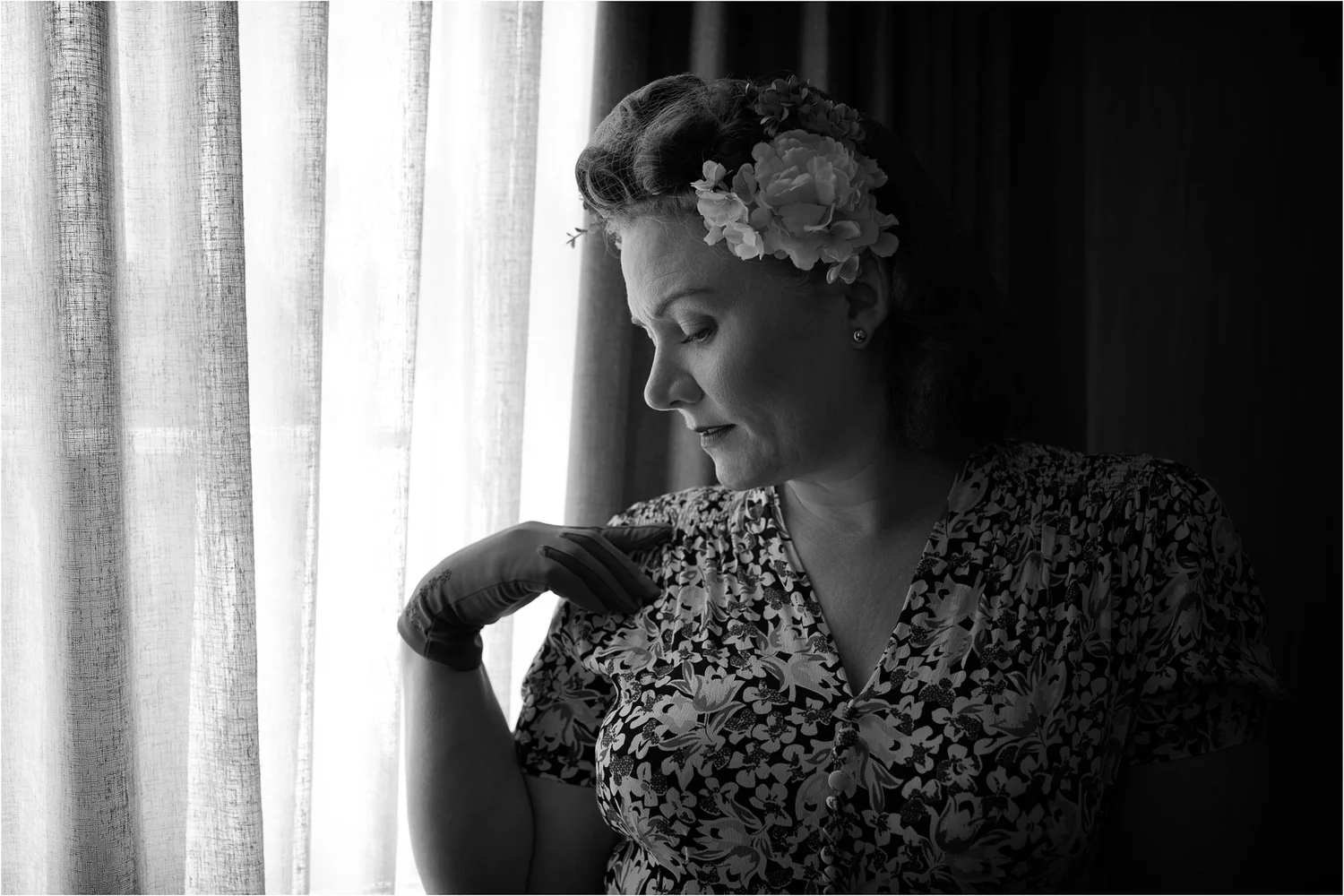 Black and white photo of Laura with flowers in her hair by a window