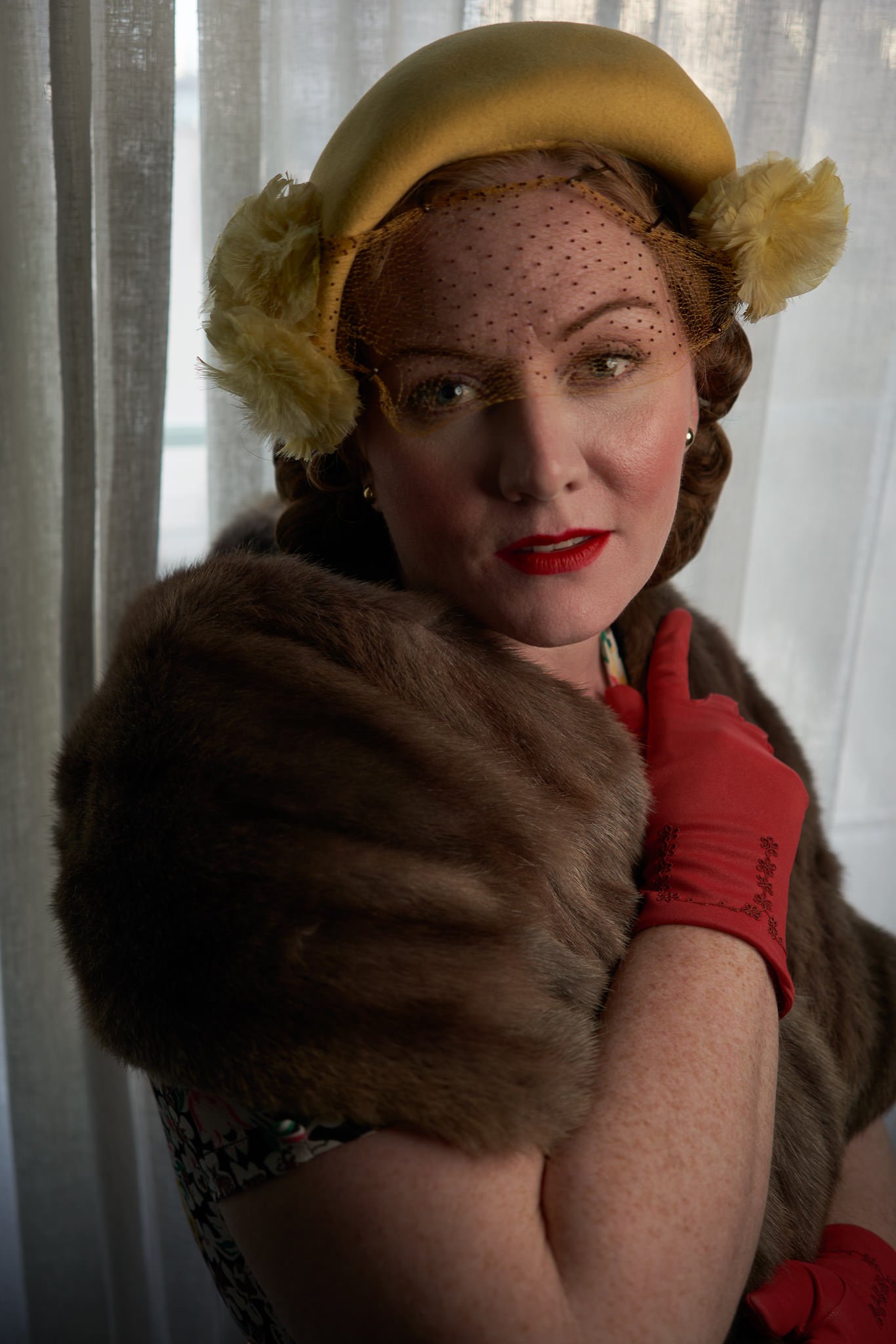 Laura in a yellow hat, fur stole and red gloves