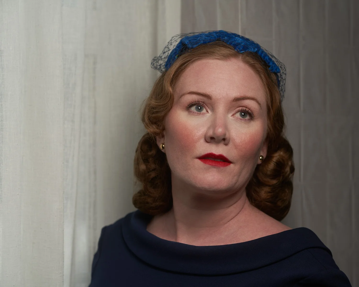 Close portrait of Laura in a navy dress and blue headpiece