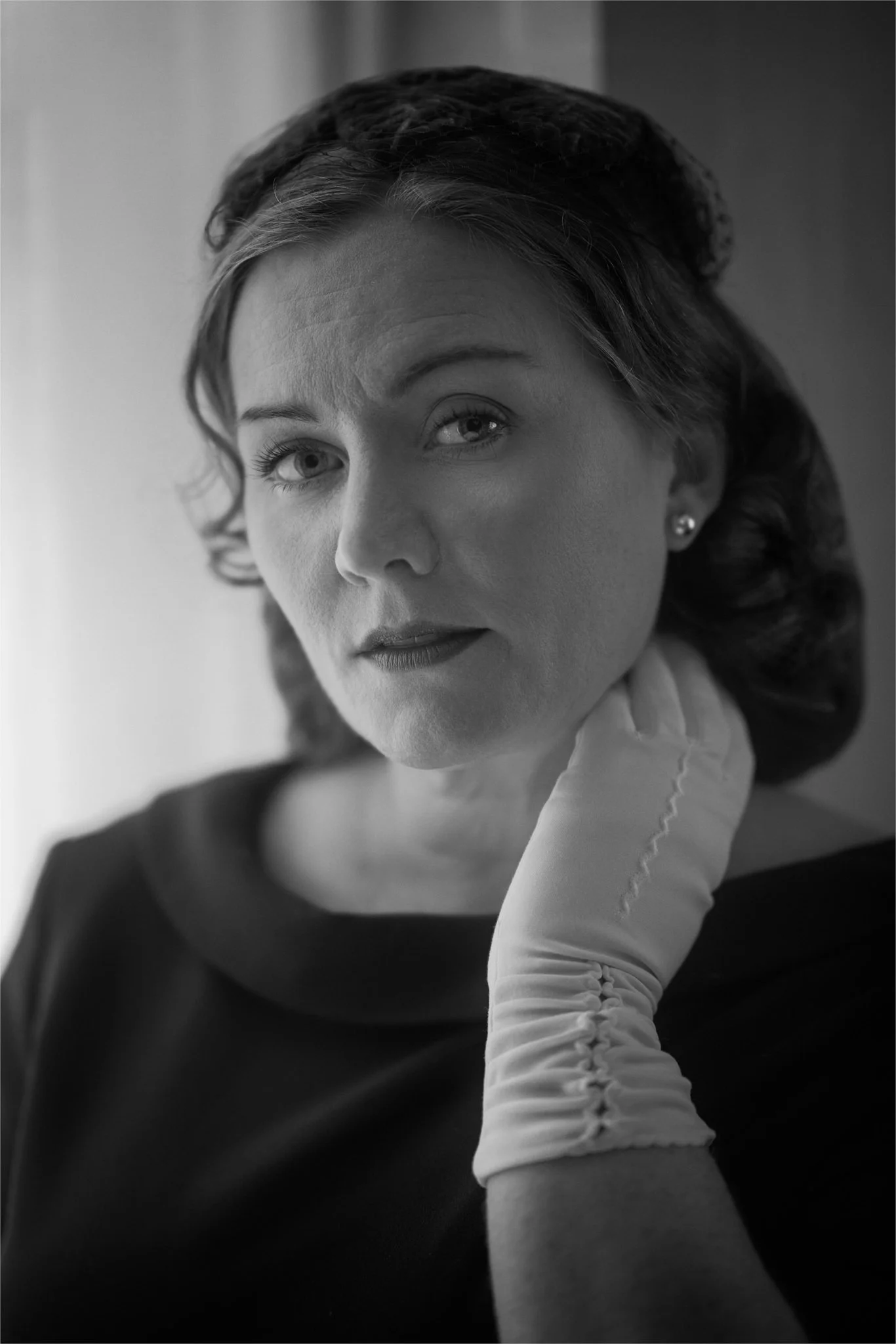 Black and white photo of Laura with a gloved hand at her neck