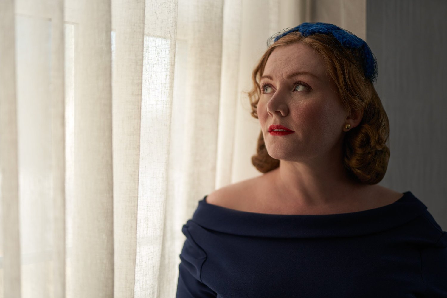 Laura looks over her shoulder in a navy dress