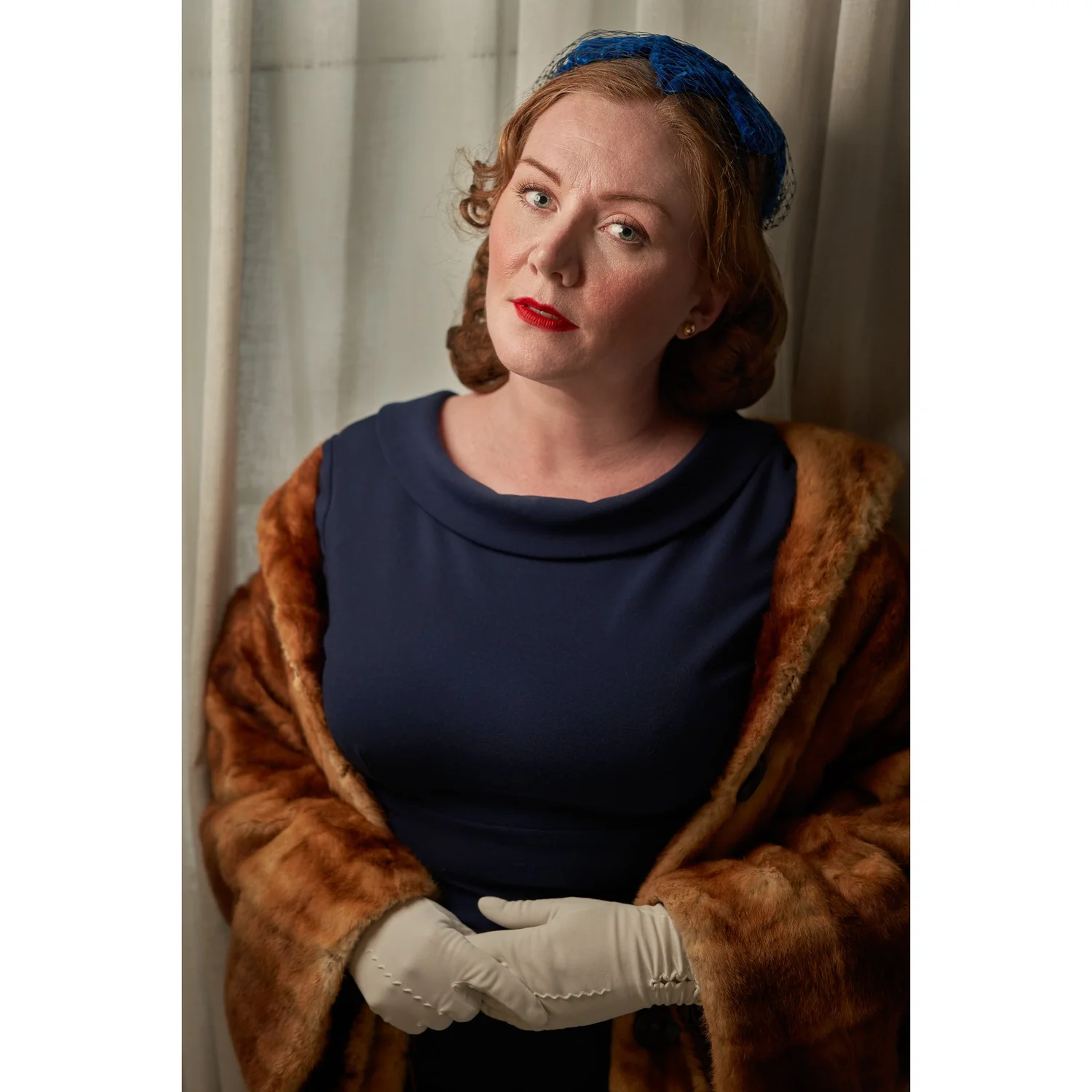 Laura in navy with a fur coat draped on her shoulders
