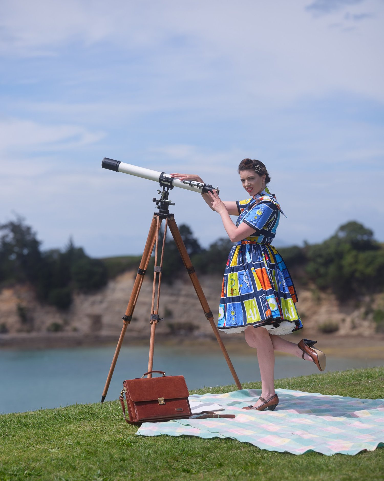 Jay peers through a vintage telescope with the sea behind