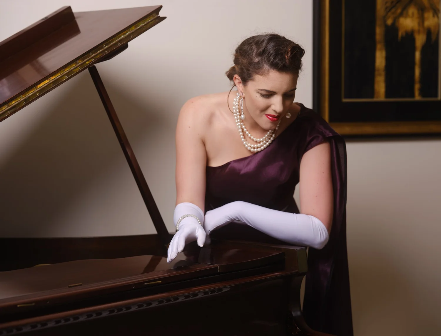 Jay looks down at the piano in a purple gown