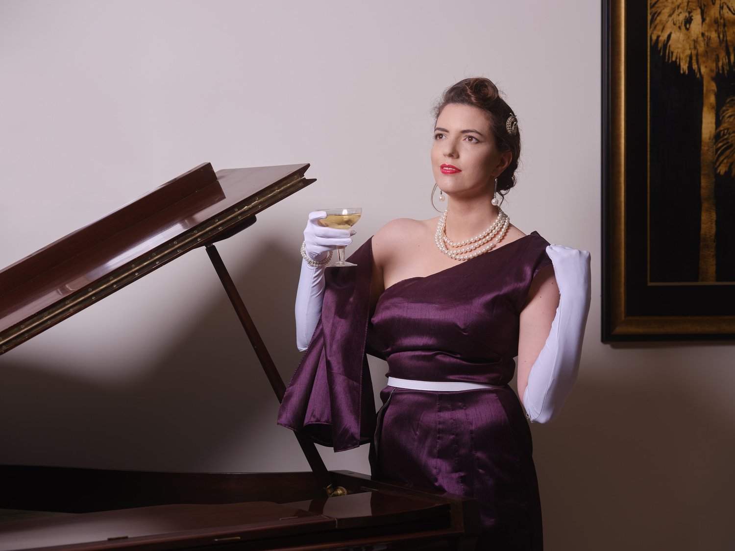 Jay holds a cocktail glass beside the piano